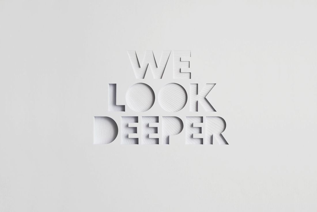 Text 'We Look Deeper' cut out on paper.