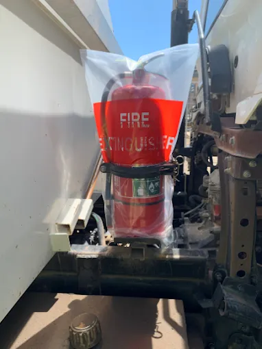Row of Red and Green Fire Suppression Cylinders with Connected Piping Against a White Wall in A Facility — Test Right Services in Ayr, QLD