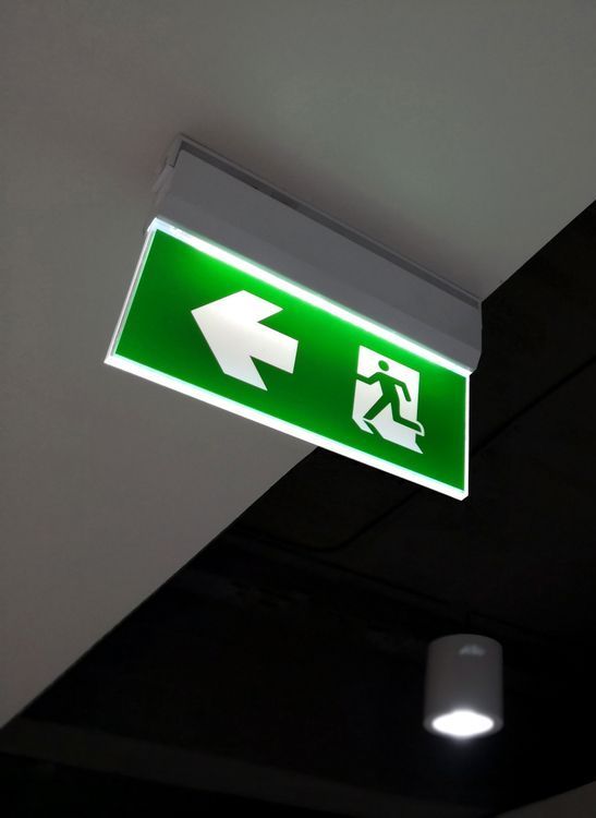 A Green Exit Sign With An Arrow Pointing To The Left — Test Right Services in Townsville, QLD