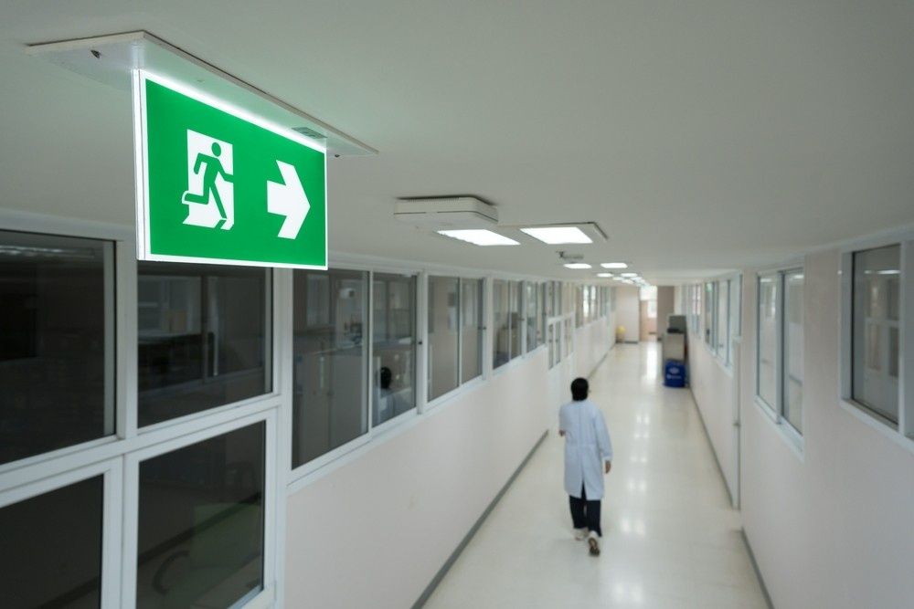 A Hallway With Stairs And A Green Exit Sign — Test Right Services in Ingham, QLD