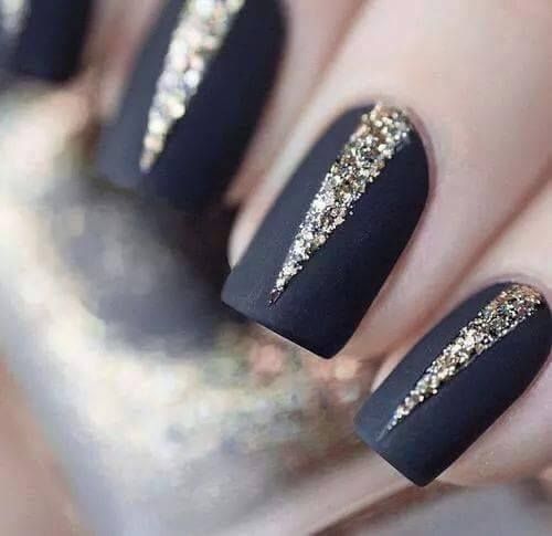 Unghie nere opache con dettagli diagonali glitterati dorati.
