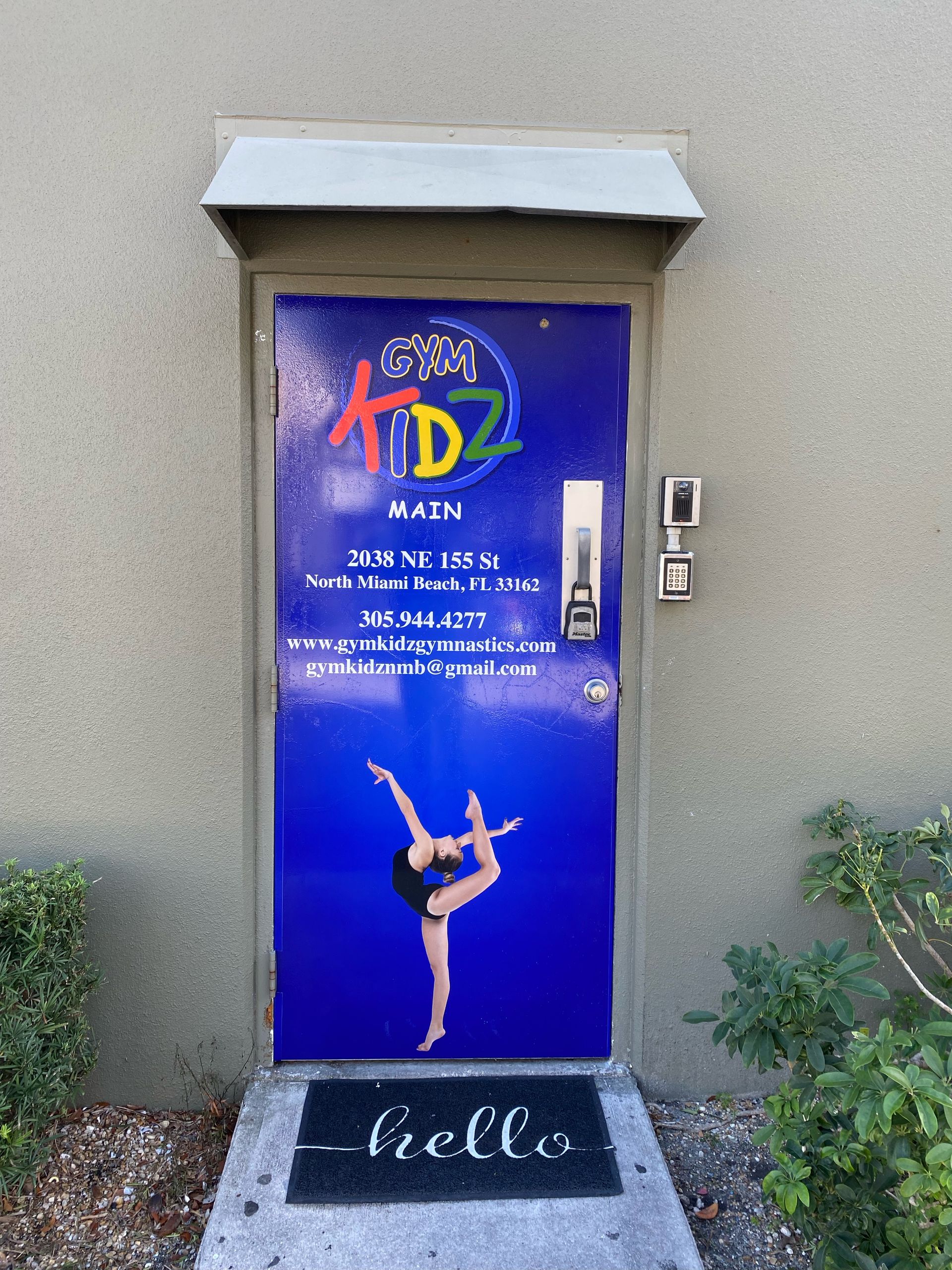 Blue studio door with a dancer poster and the word “hello” on the mat