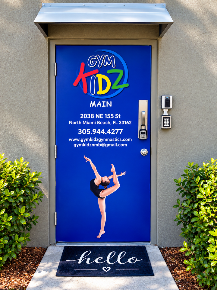 Blue dance studio entrance door with ballerina graphic, “Hello” mat, and shrubs on either side