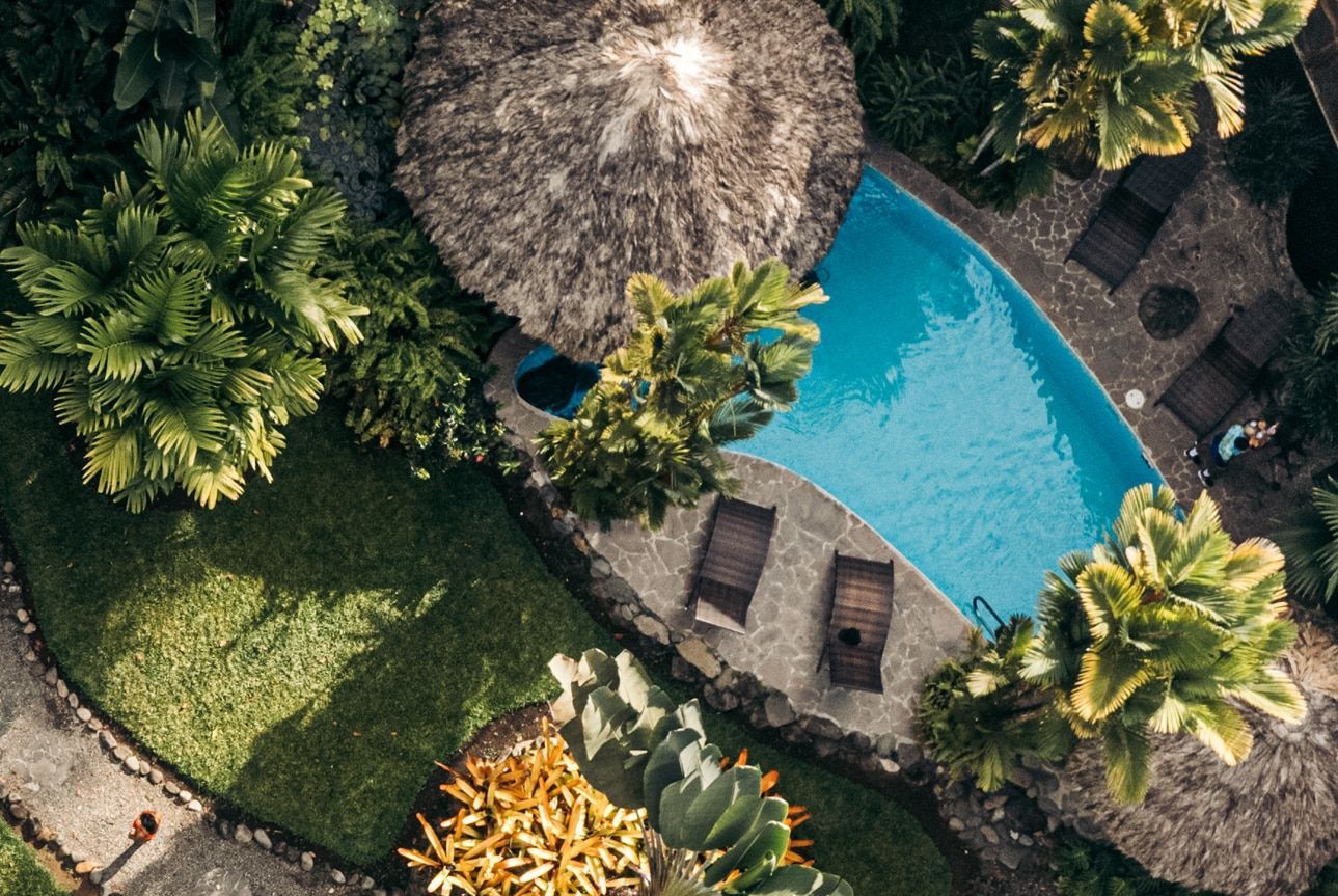 An aerial view of a swimming pool surrounded by trees and chairs.