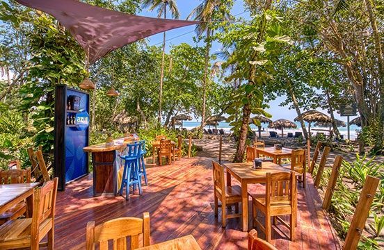 A restaurant with tables and chairs on a wooden deck surrounded by trees.