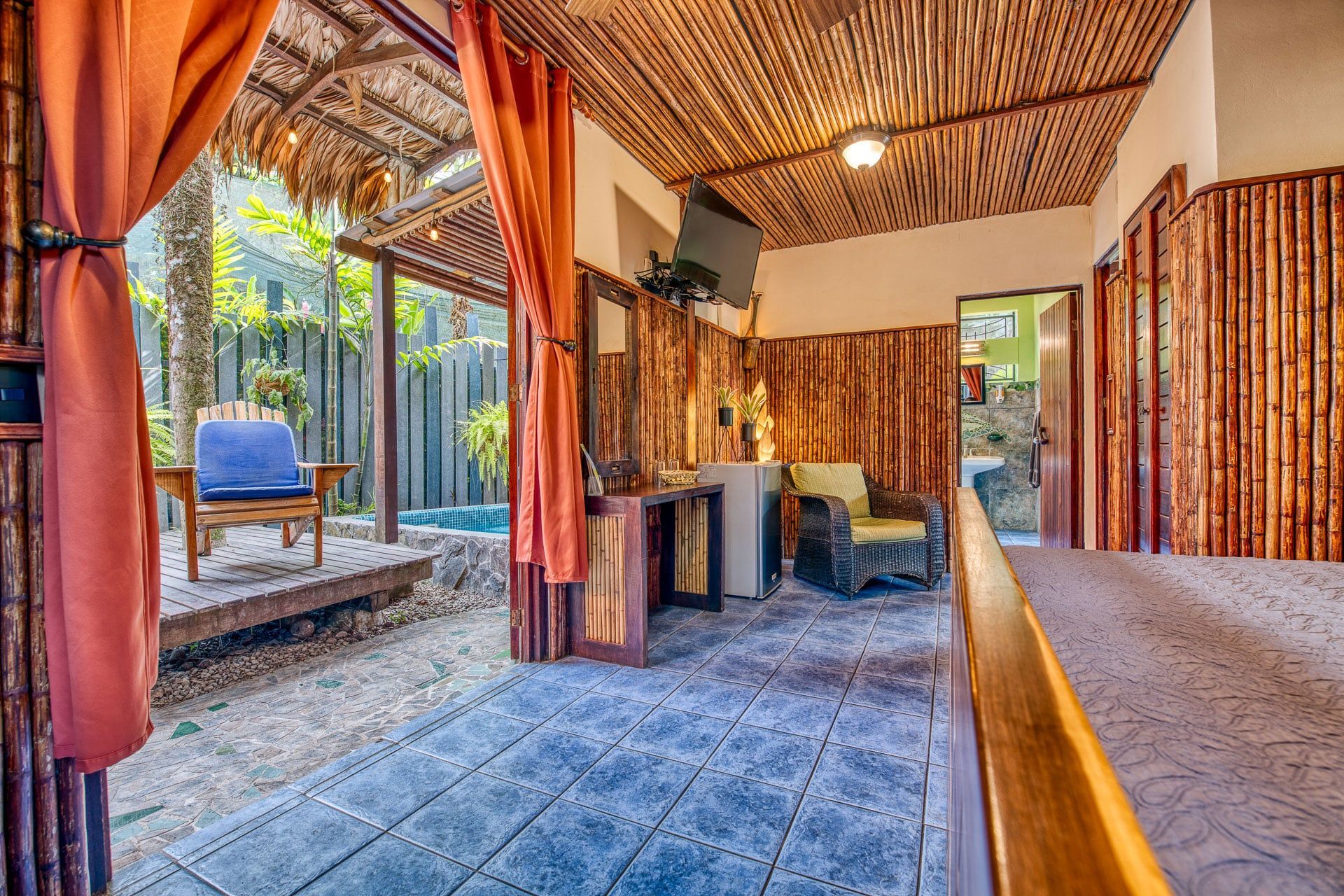 A room with a wooden ceiling , a bed , a chair and a table.