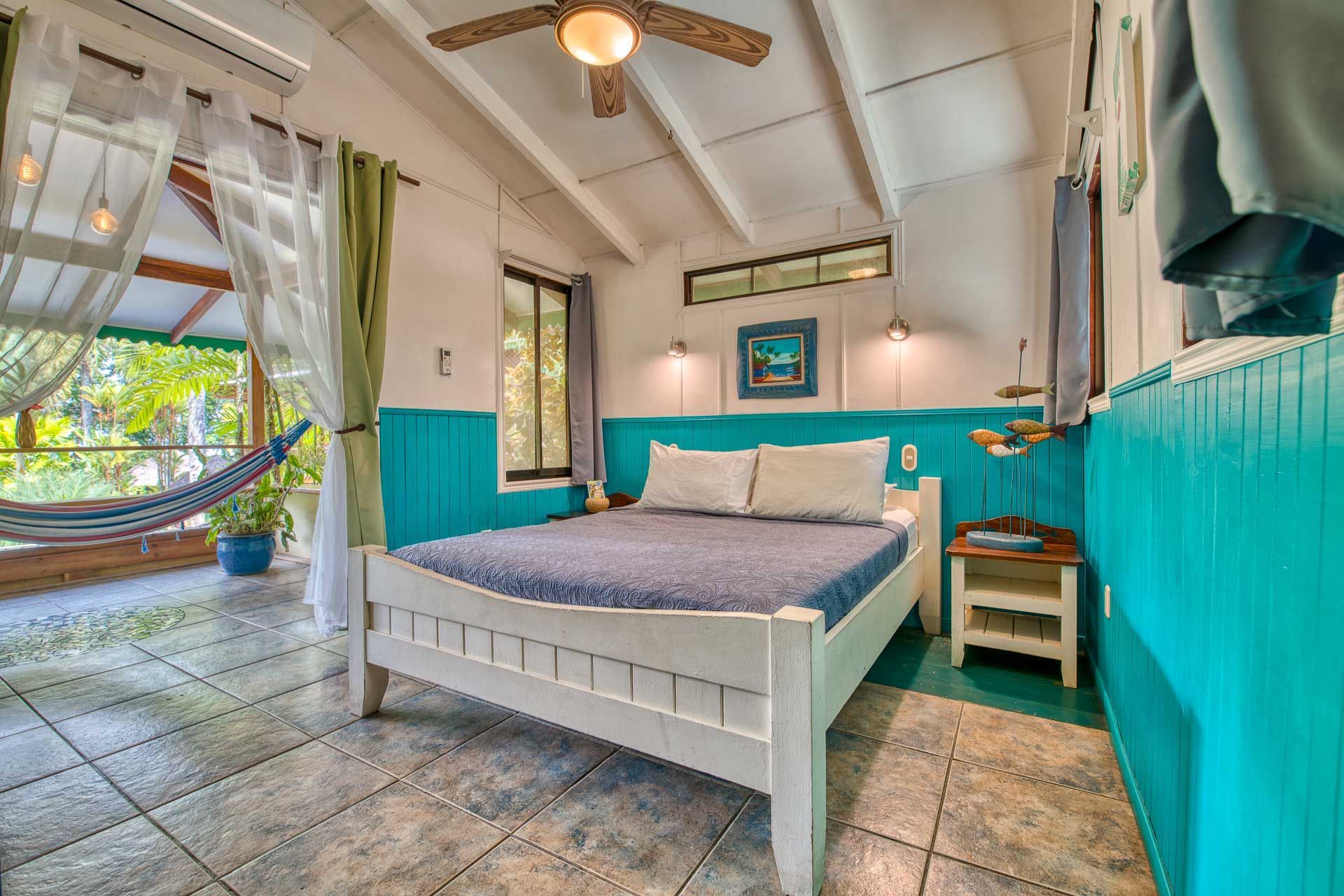 A bedroom with a king size bed and a hammock hanging from the ceiling.