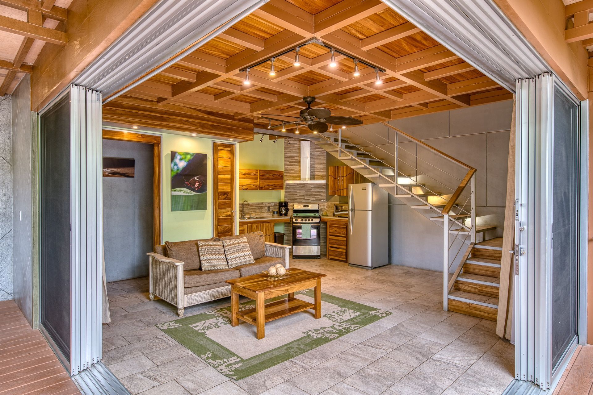 A living room with a couch , coffee table , and stairs leading to the kitchen.