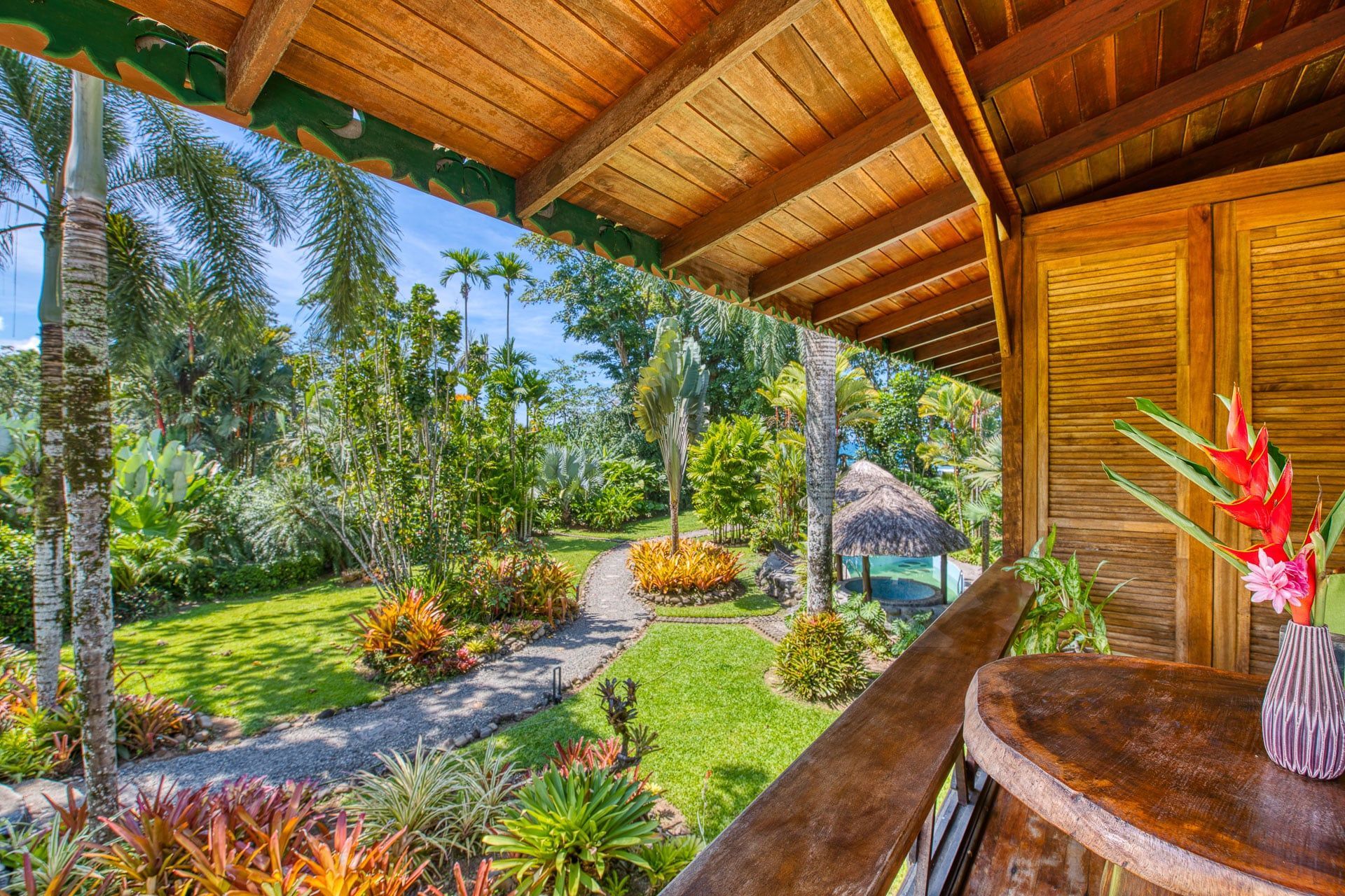 A wooden house with a balcony overlooking a lush green garden.