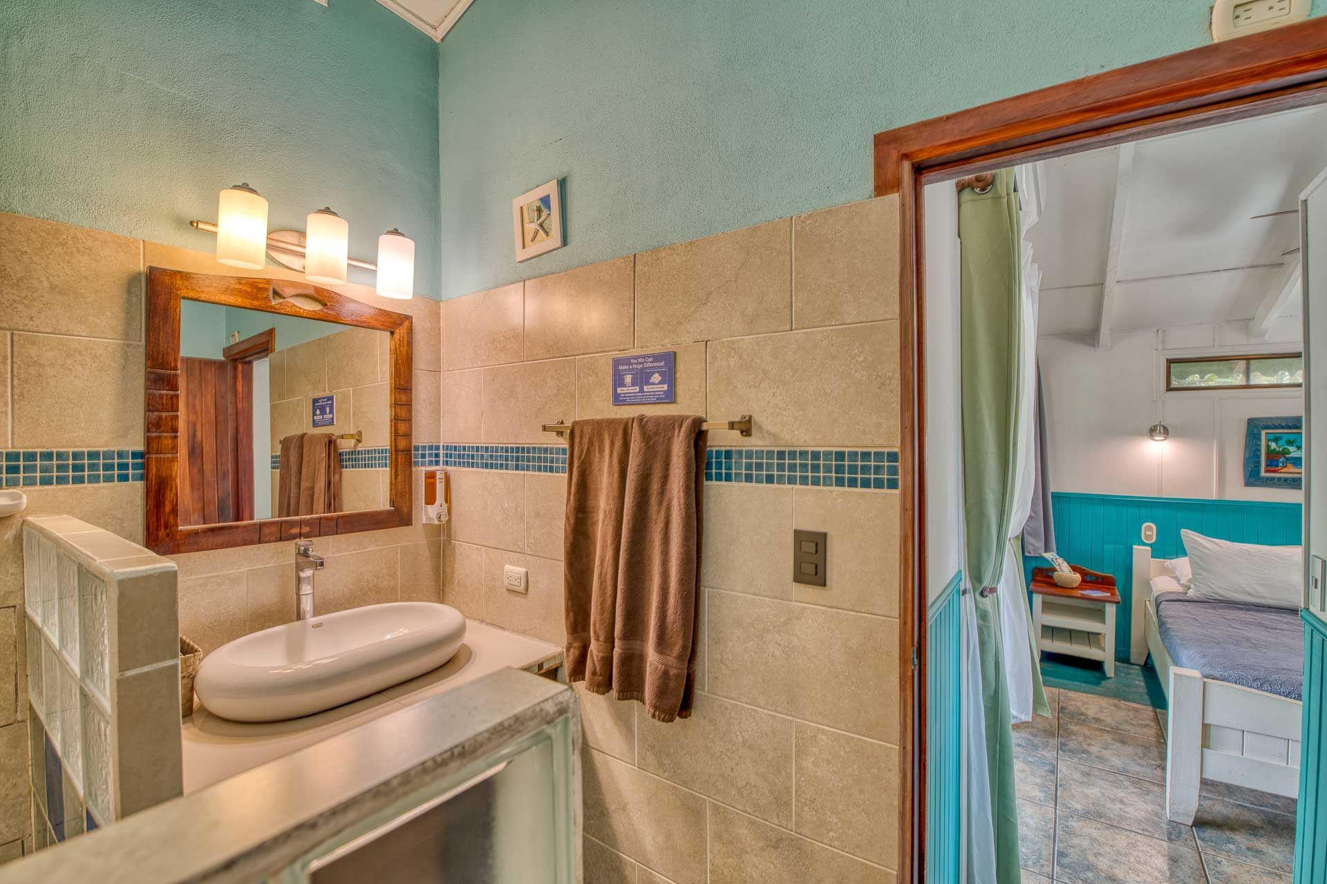 A bathroom with a sink , mirror , and towels hanging on the wall.