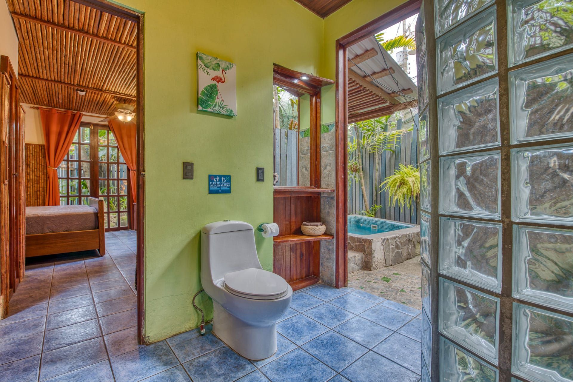 A bathroom with a toilet and a glass door leading to a pool.