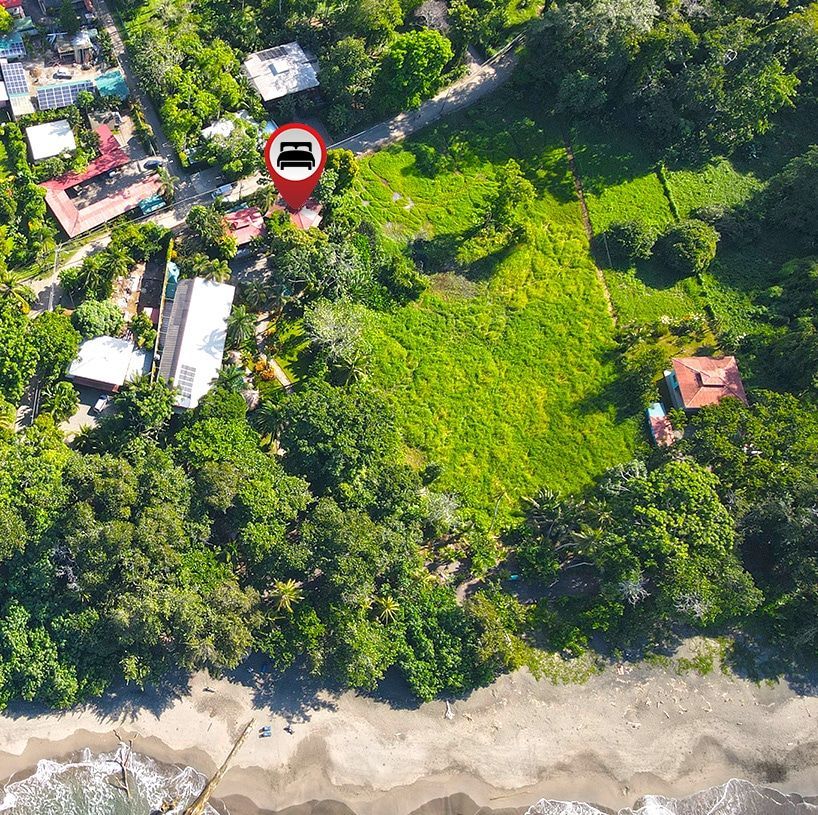 An aerial view of a lush green field with a car in a red pin