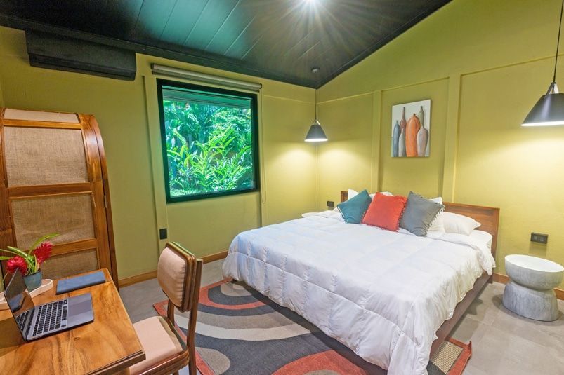 A bedroom with a large bed , desk , chair and window.