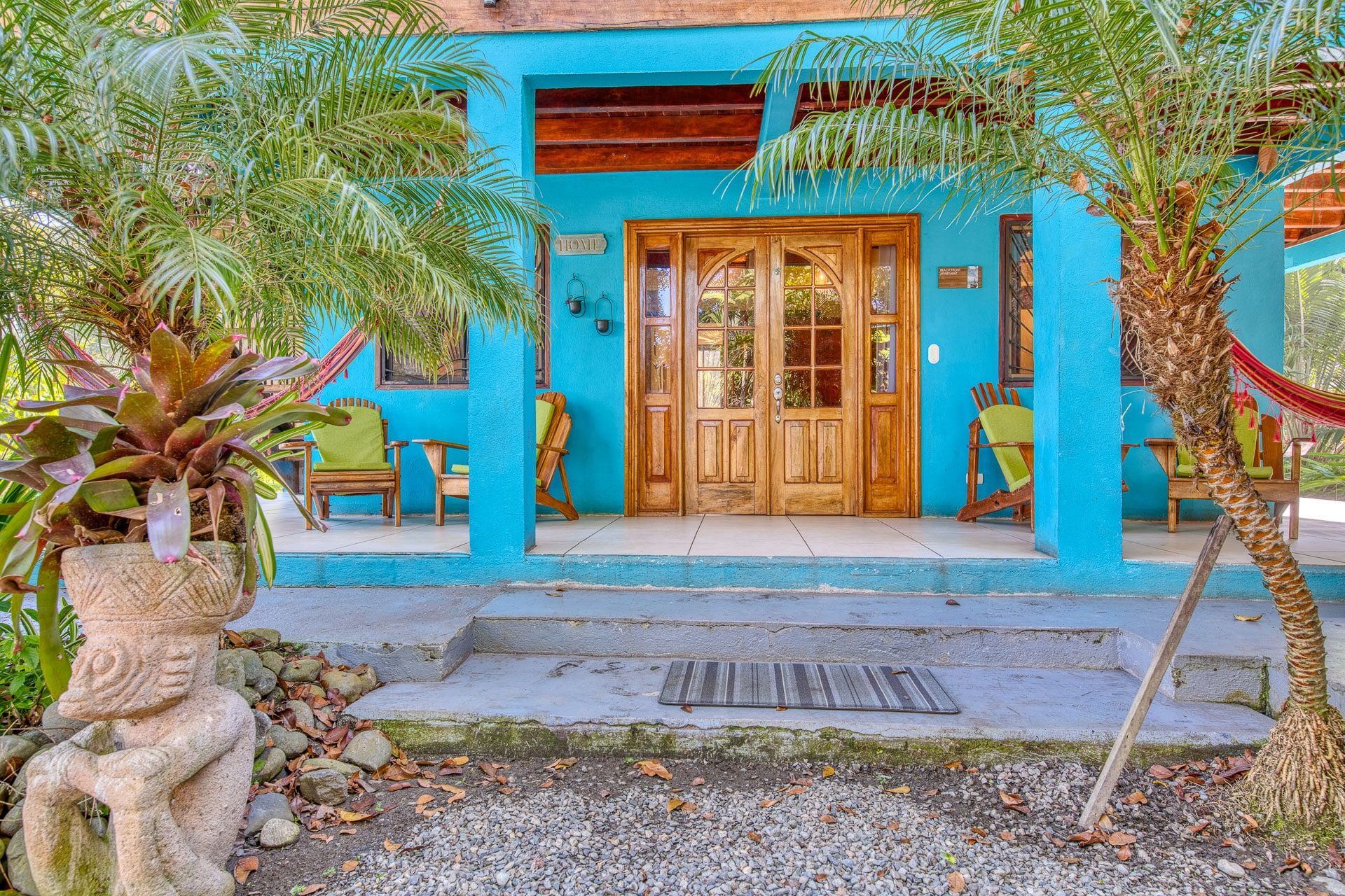 A blue house with a porch and a hammock in front of it.