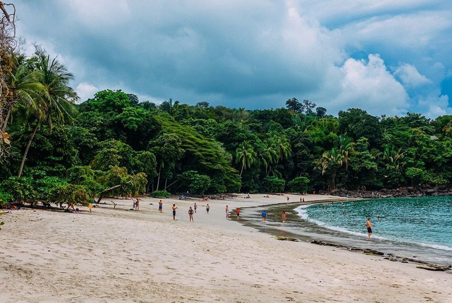 A group of people are walking on a beach near the ocean.