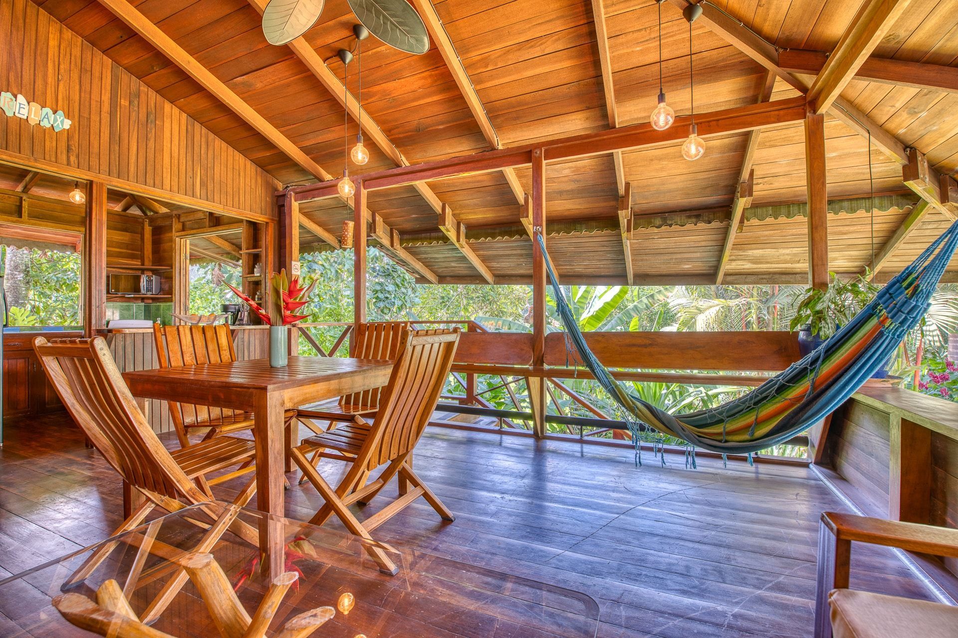 A wooden porch with a table and chairs and a hammock.