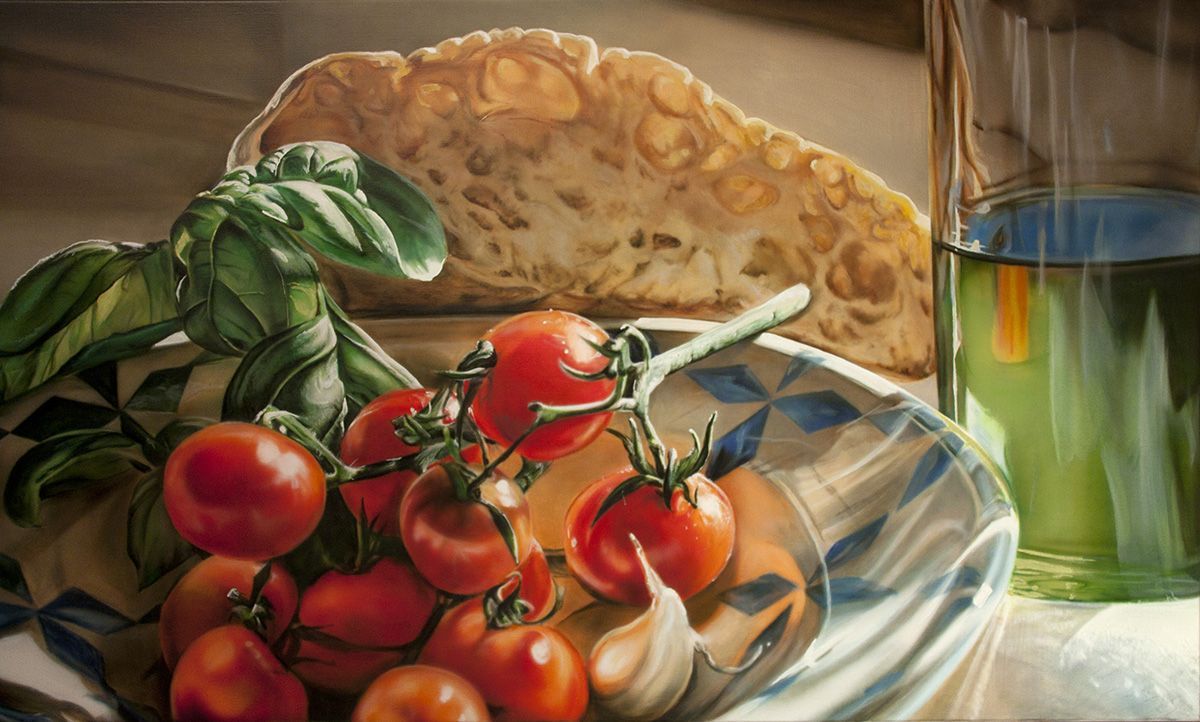 Close-up van verse tomaten, basilicum, knapperig brood en olijfolie in een glas in een kom met een blauw en wit patroon.