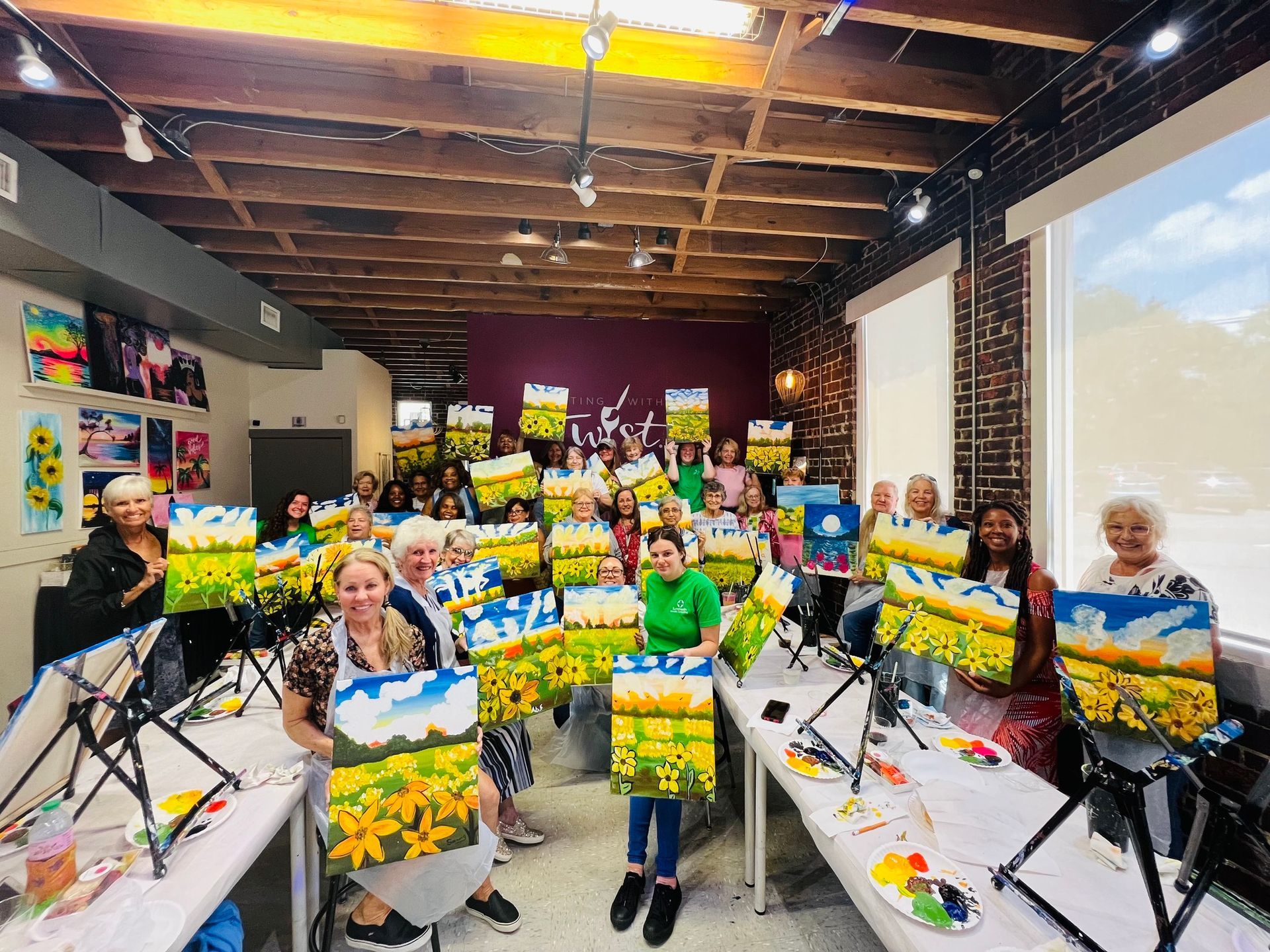 A group of people are standing in a room holding paintings.