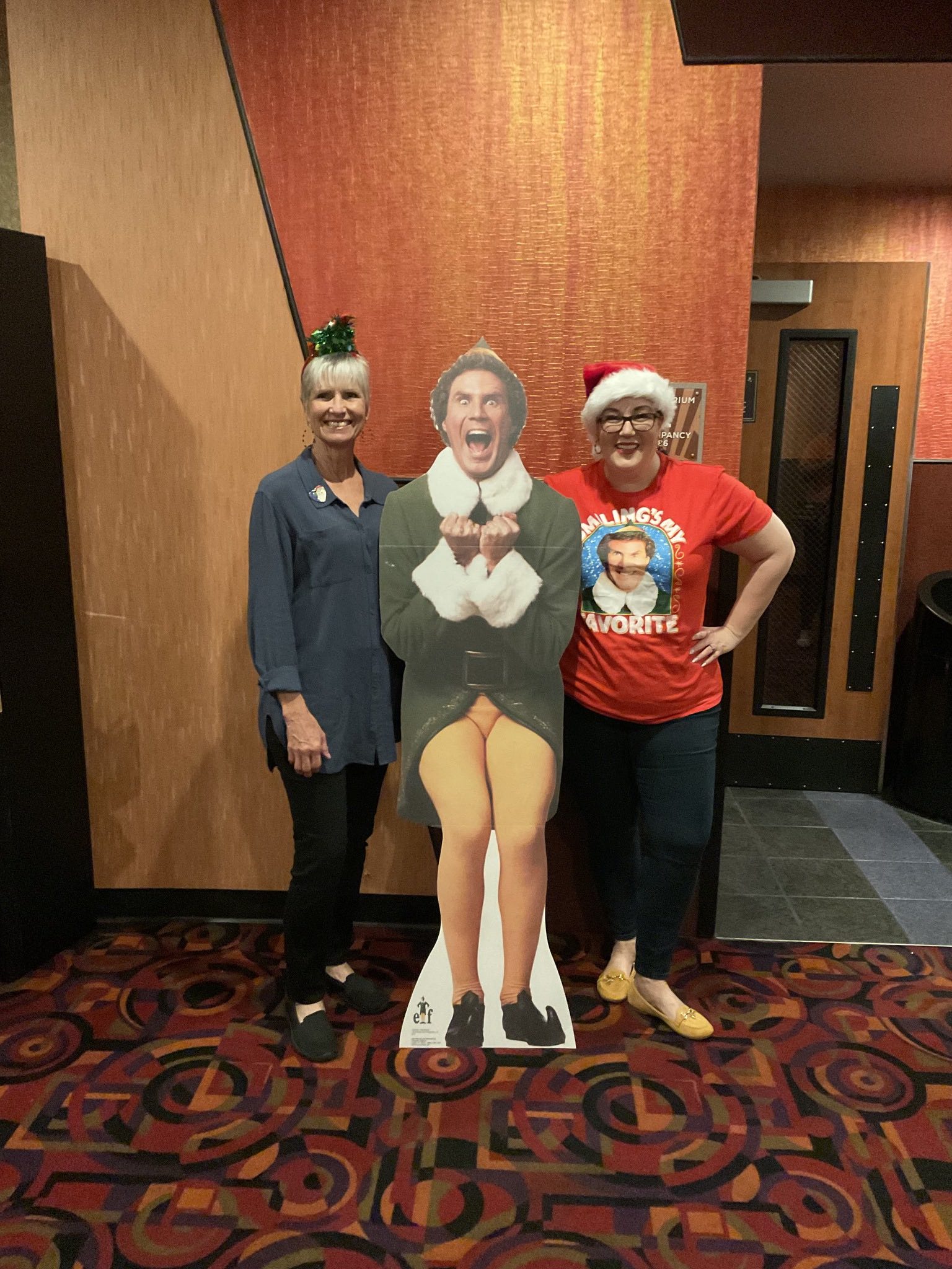 Two women are standing next to a cardboard cutout of a man.