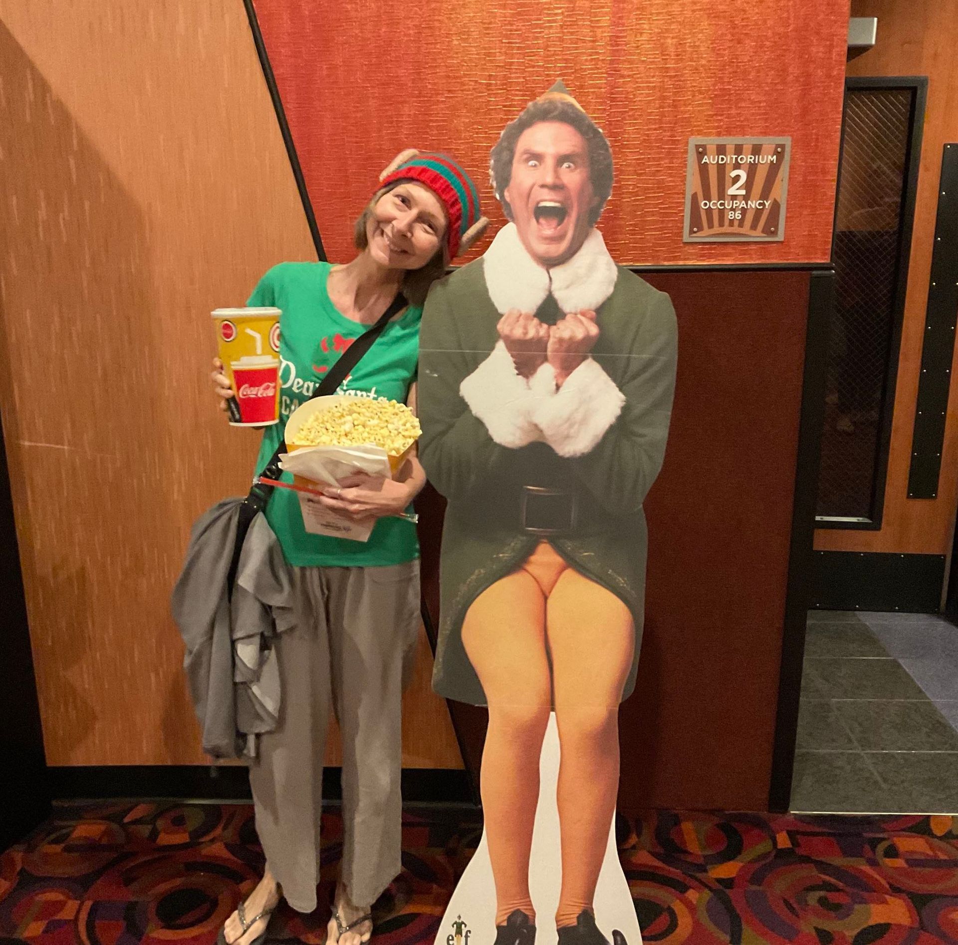 A woman standing next to a cardboard cutout of an elf