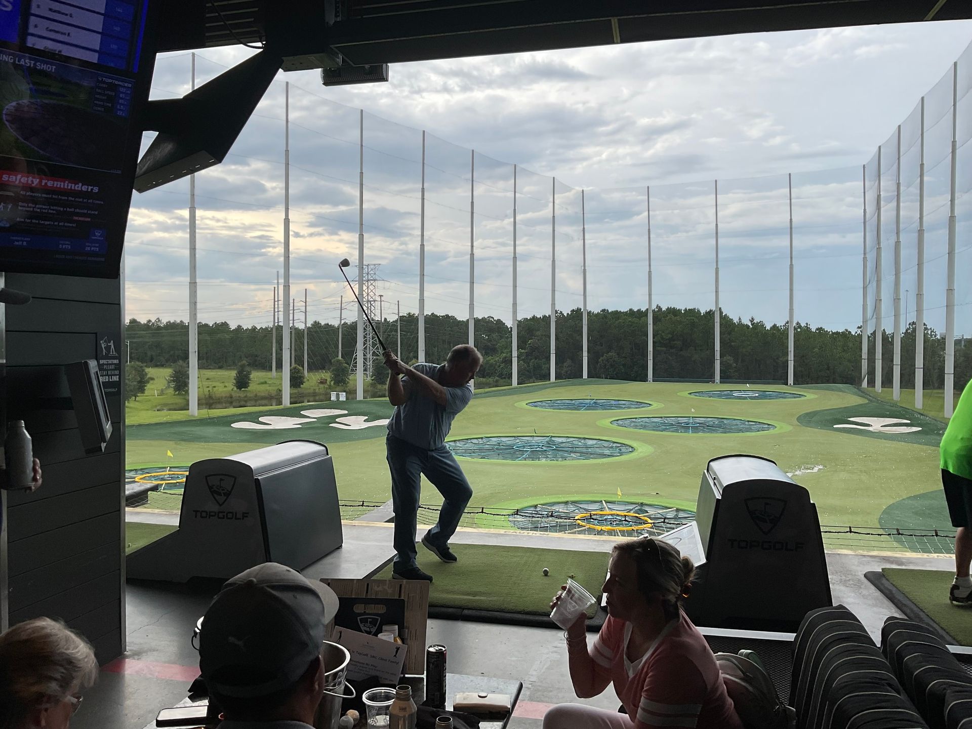 A man is swinging a golf club at a golf course while people watch.