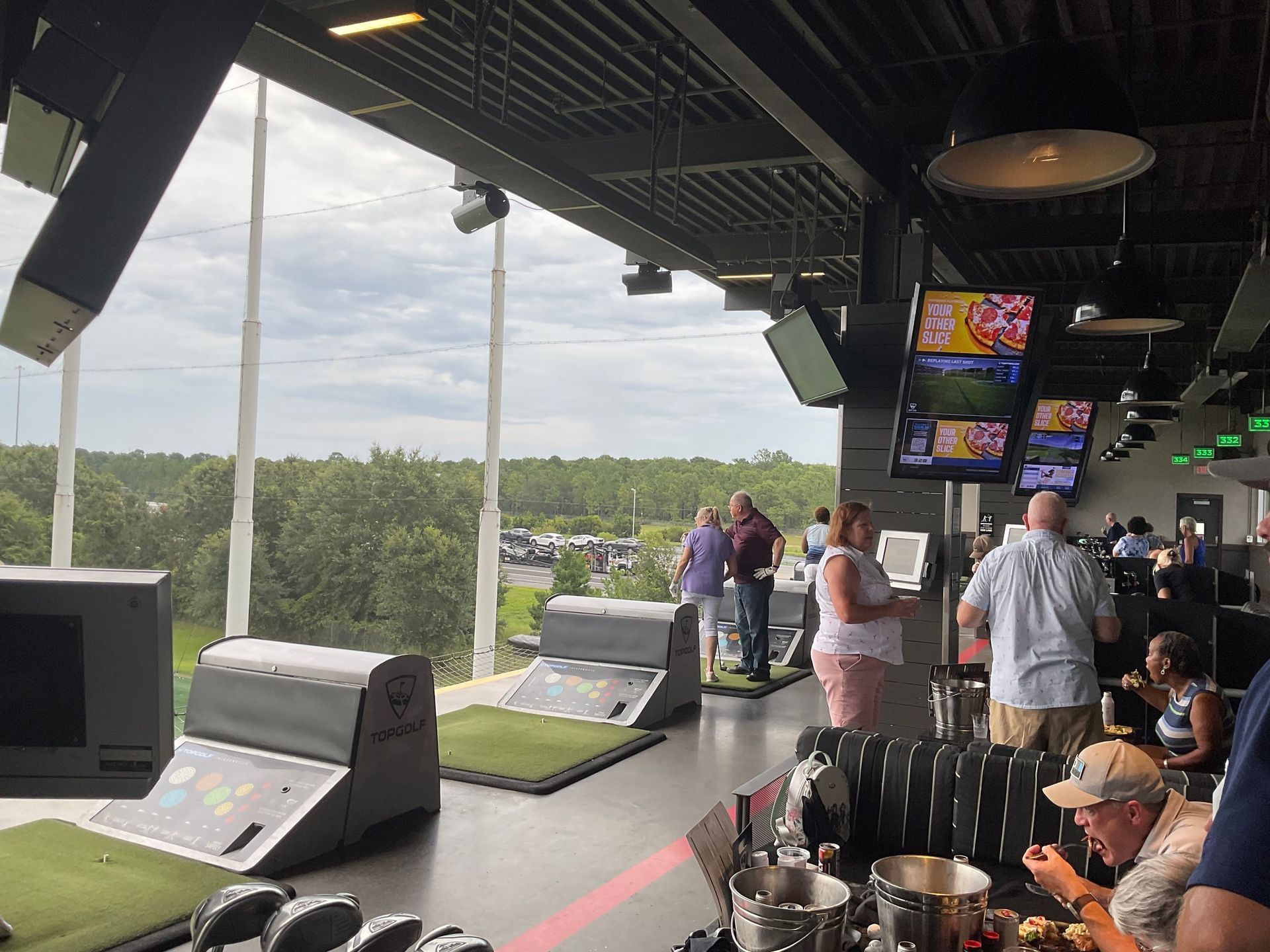 A group of people are sitting at a table in a restaurant with a view of a golf course.
