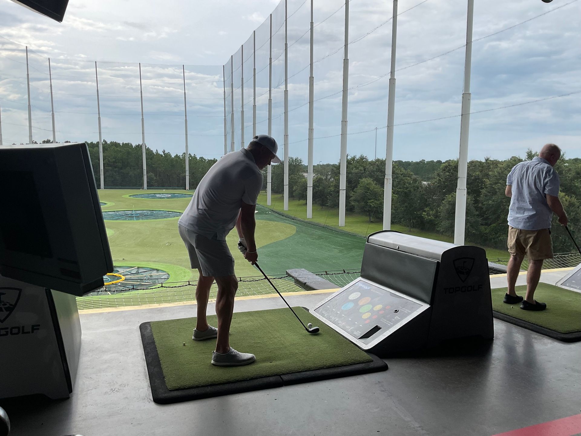 Two men are playing golf on a driving range.