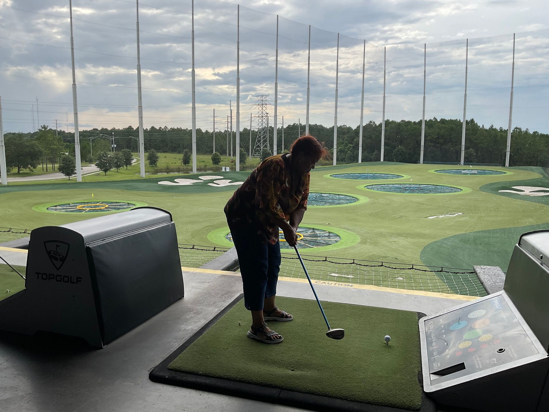 A woman is swinging a golf club on a driving range.