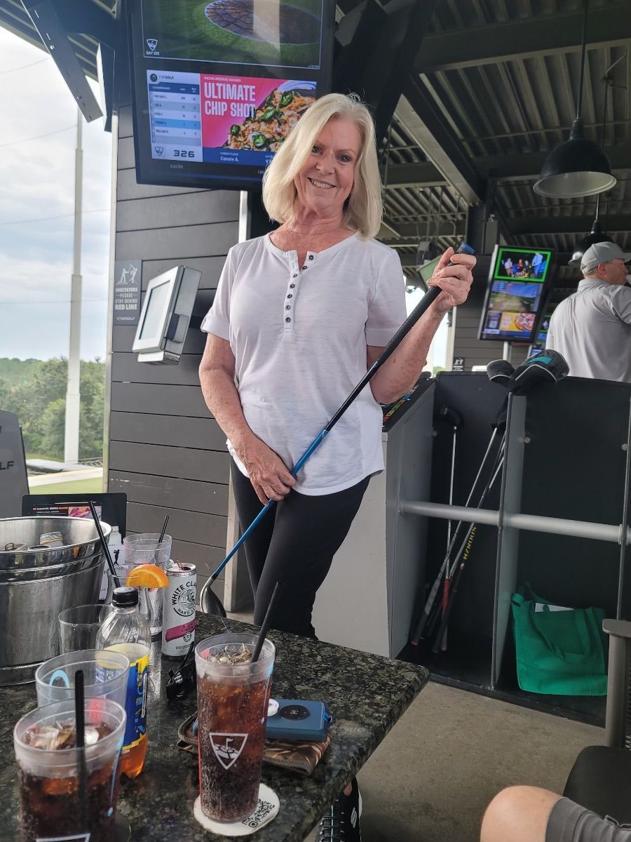 A woman is holding a golf club at a bar.
