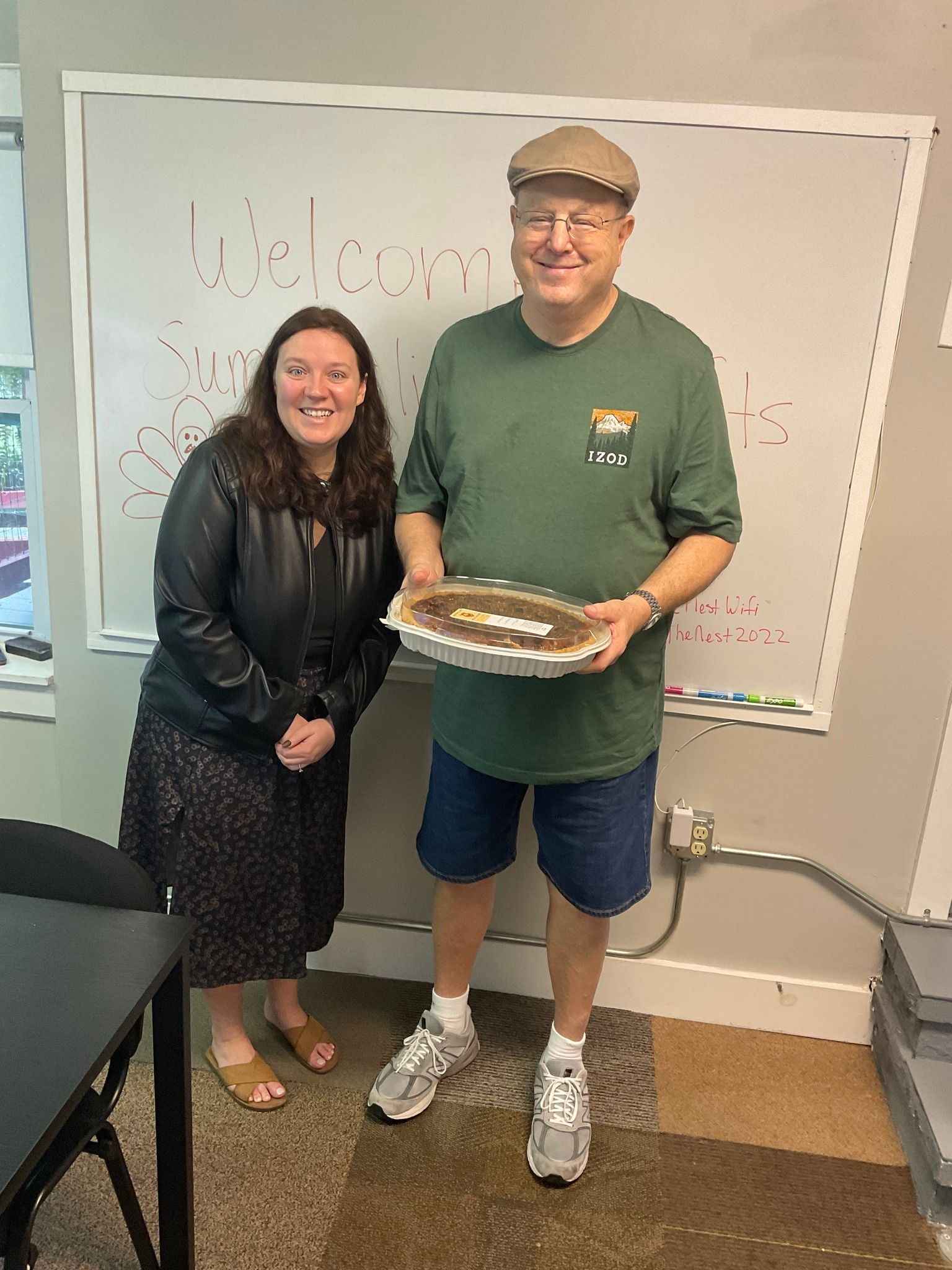 A man and a woman are standing next to each other holding a tray of food.