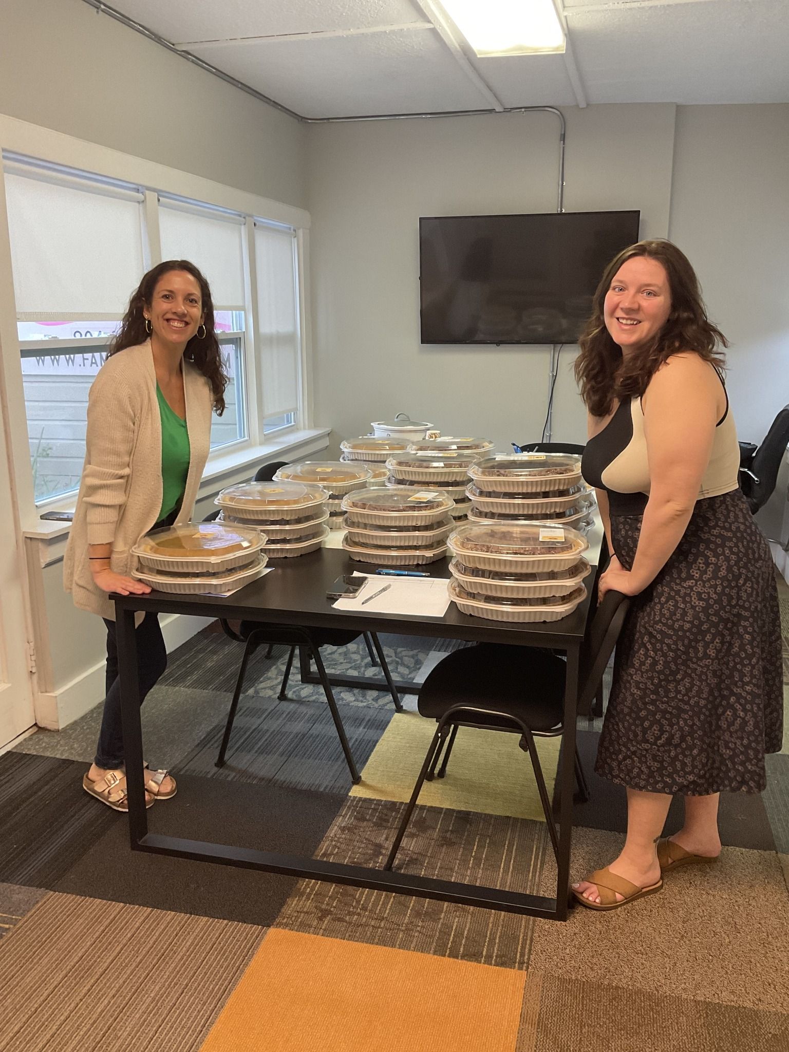 Two women are standing next to a table filled with plates of food.