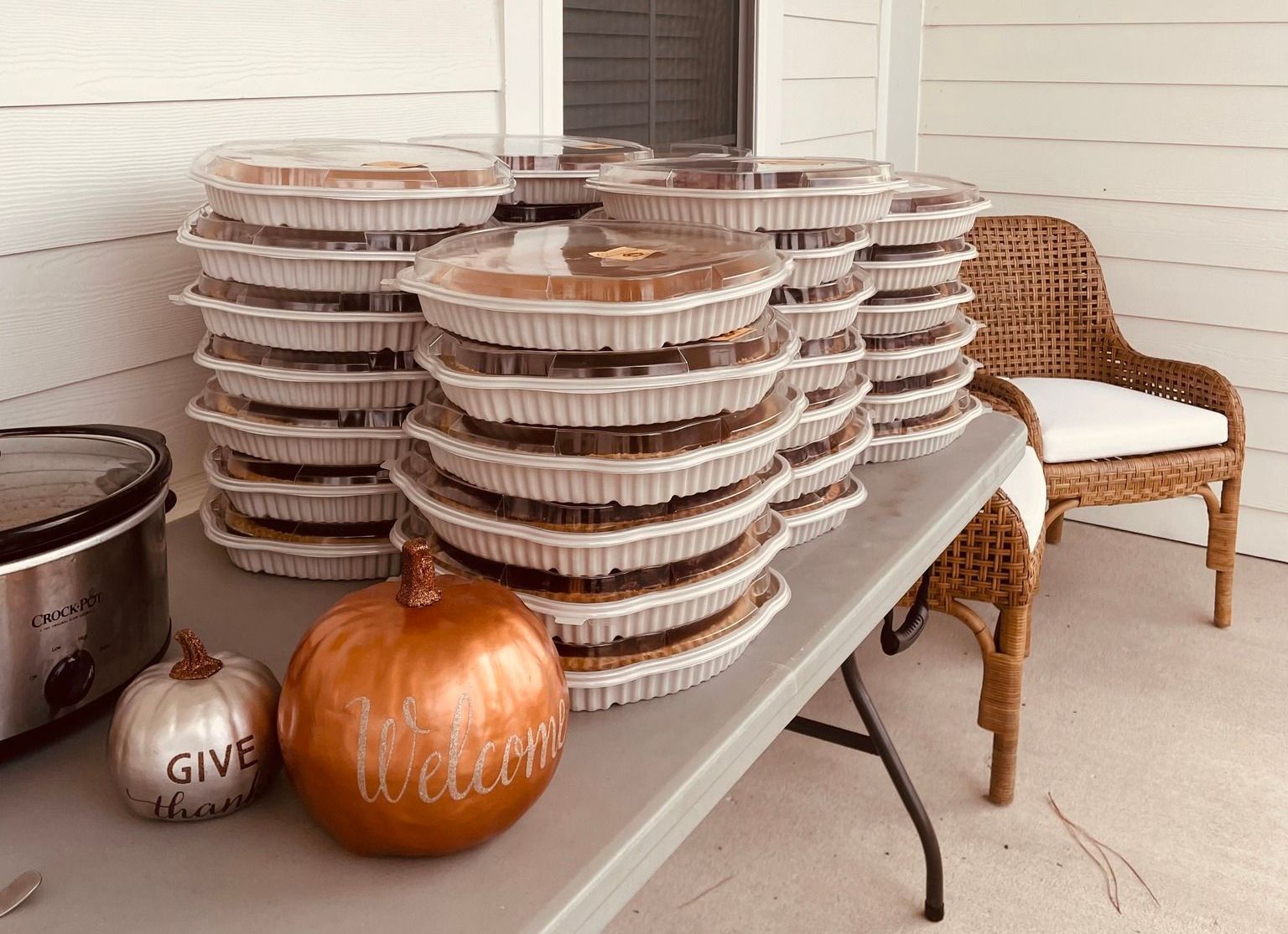 A table topped with a stack of pies and a pumpkin.