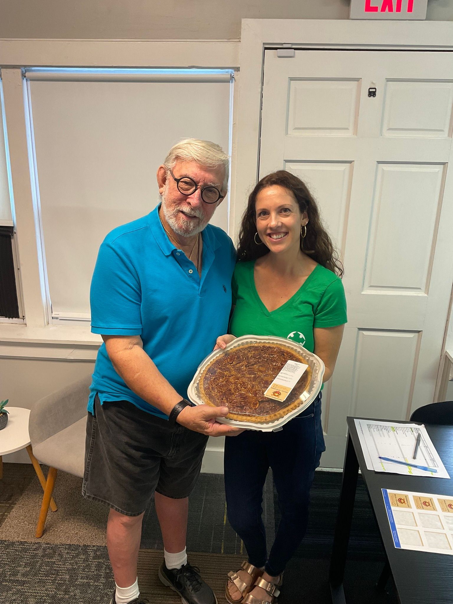 A man and a woman are standing next to each other holding a pie.