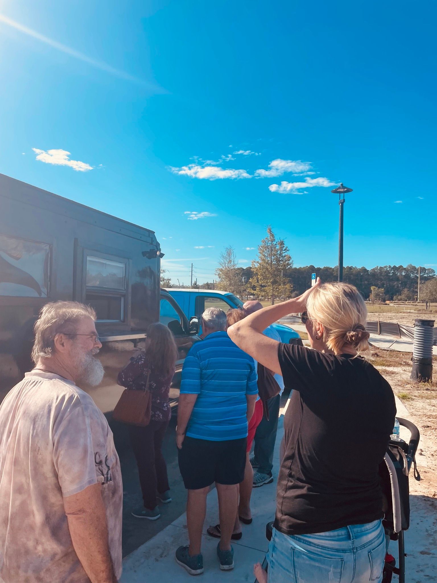 A group of people are standing in front of a rv.