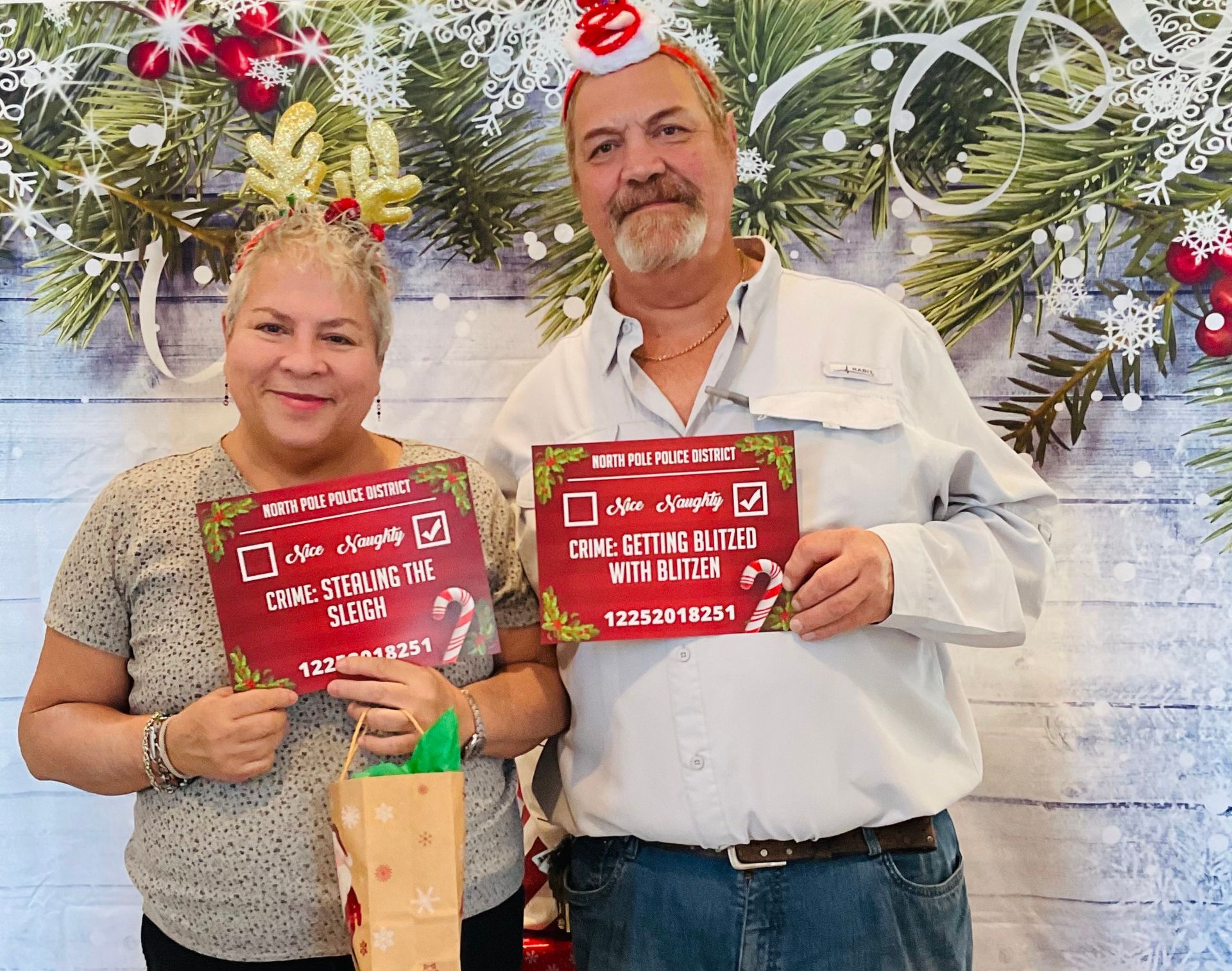A man and a woman are holding signs in front of a christmas background.