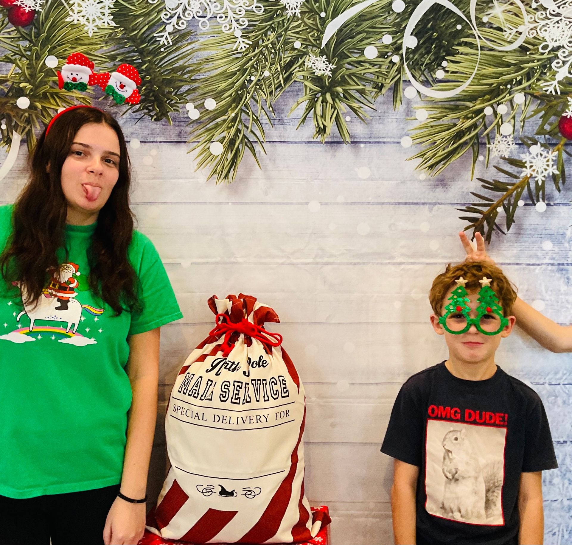 A woman and a boy are posing for a picture in front of a christmas backdrop.