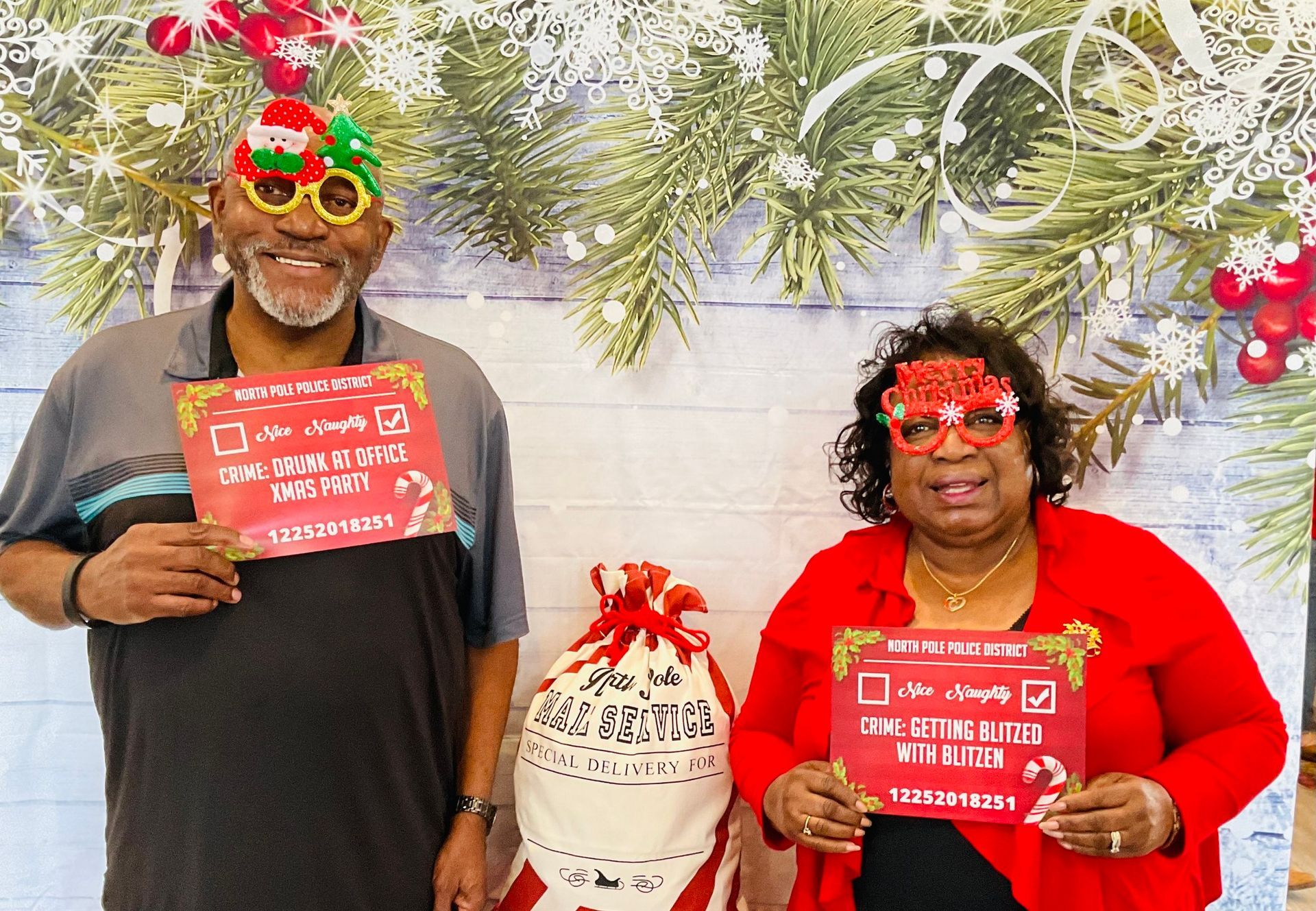 A man and a woman are holding signs in front of a christmas tree.