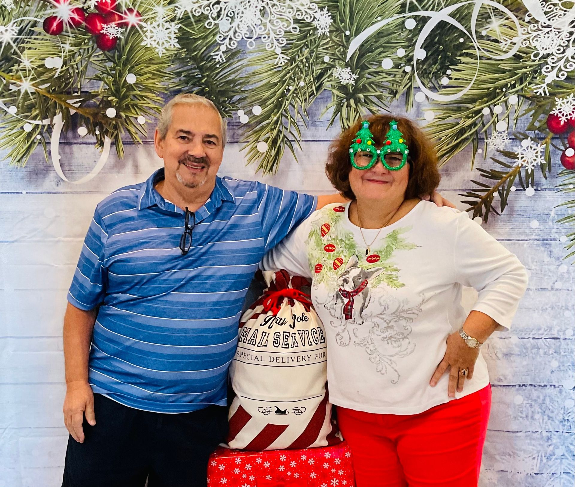 A man and a woman are posing for a picture in front of a christmas background.