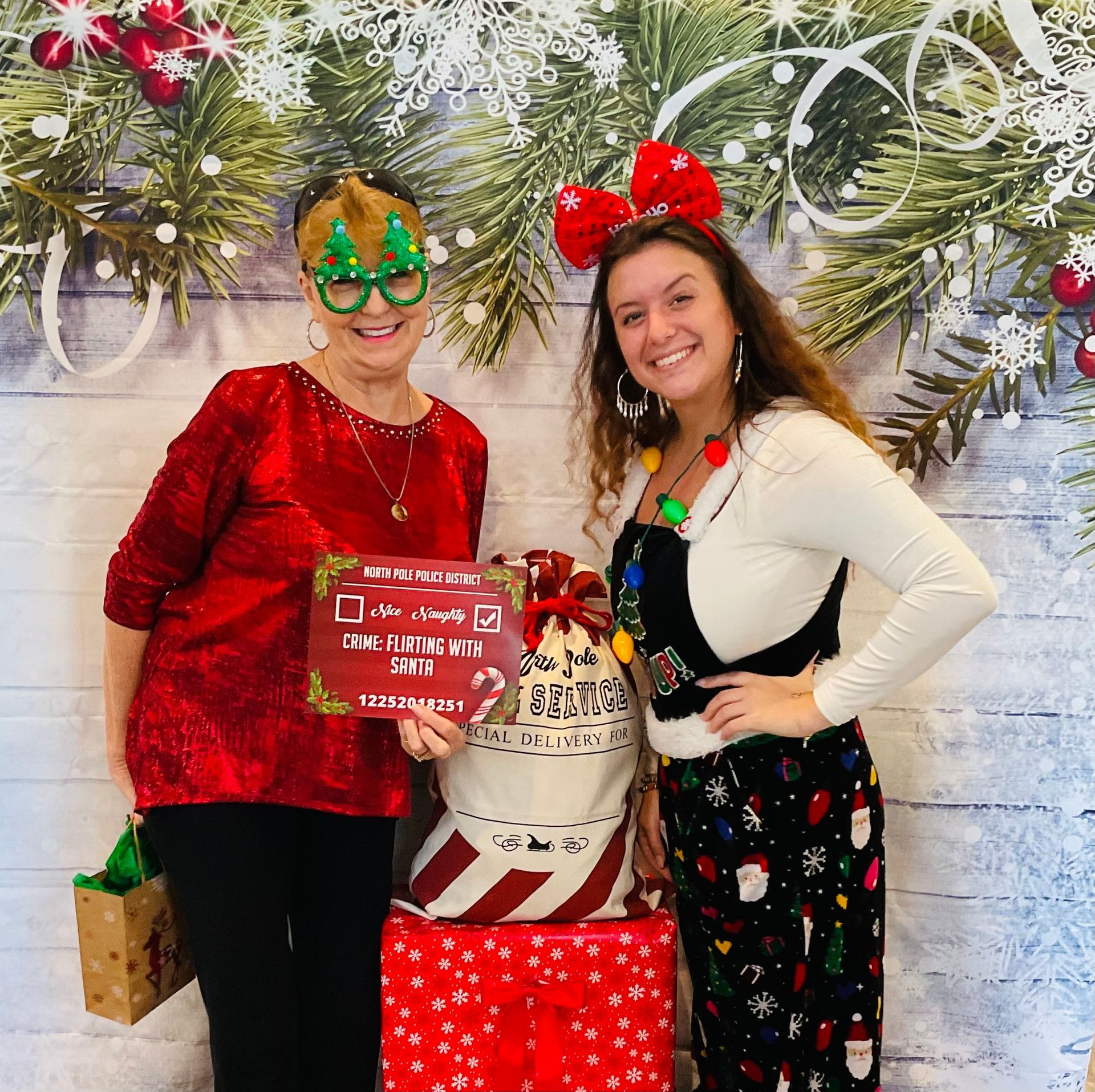 Two women are posing for a picture in front of a christmas background