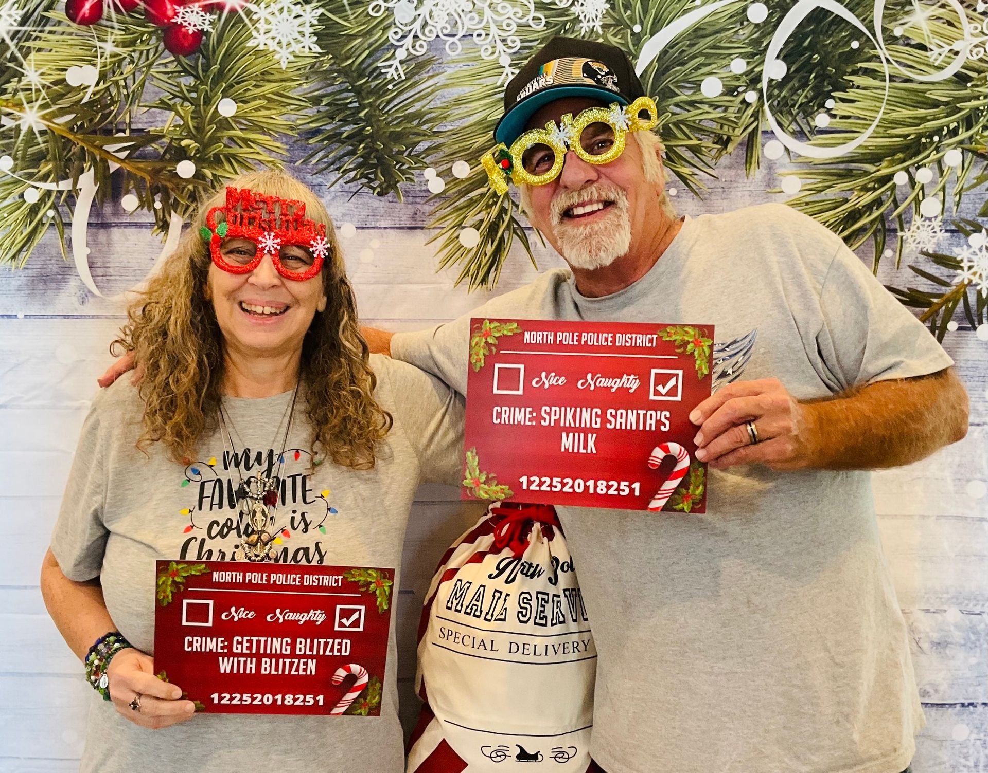 A man and a woman are holding signs in front of a christmas tree.
