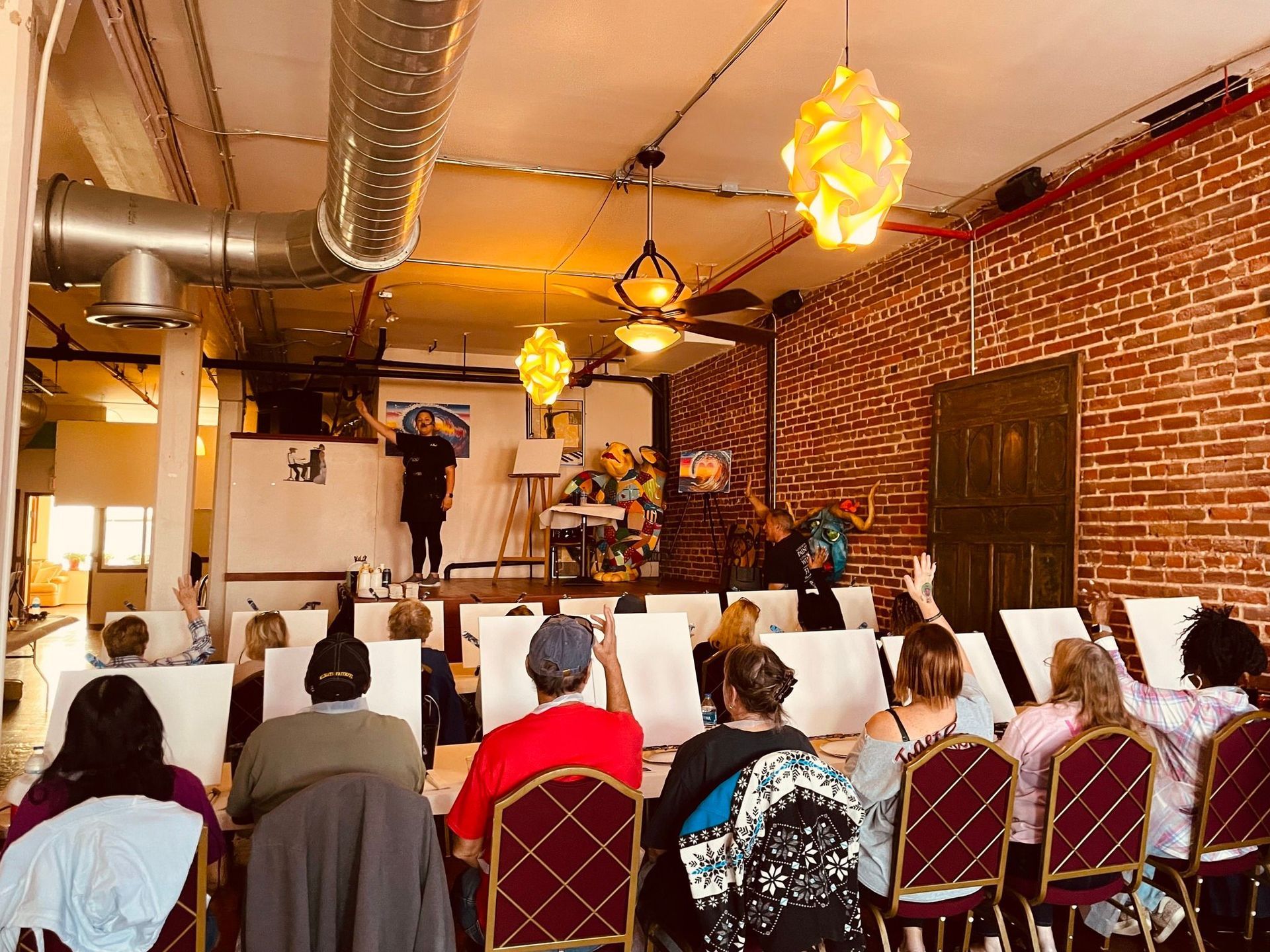 A group of people are sitting at tables in a room with a brick wall.