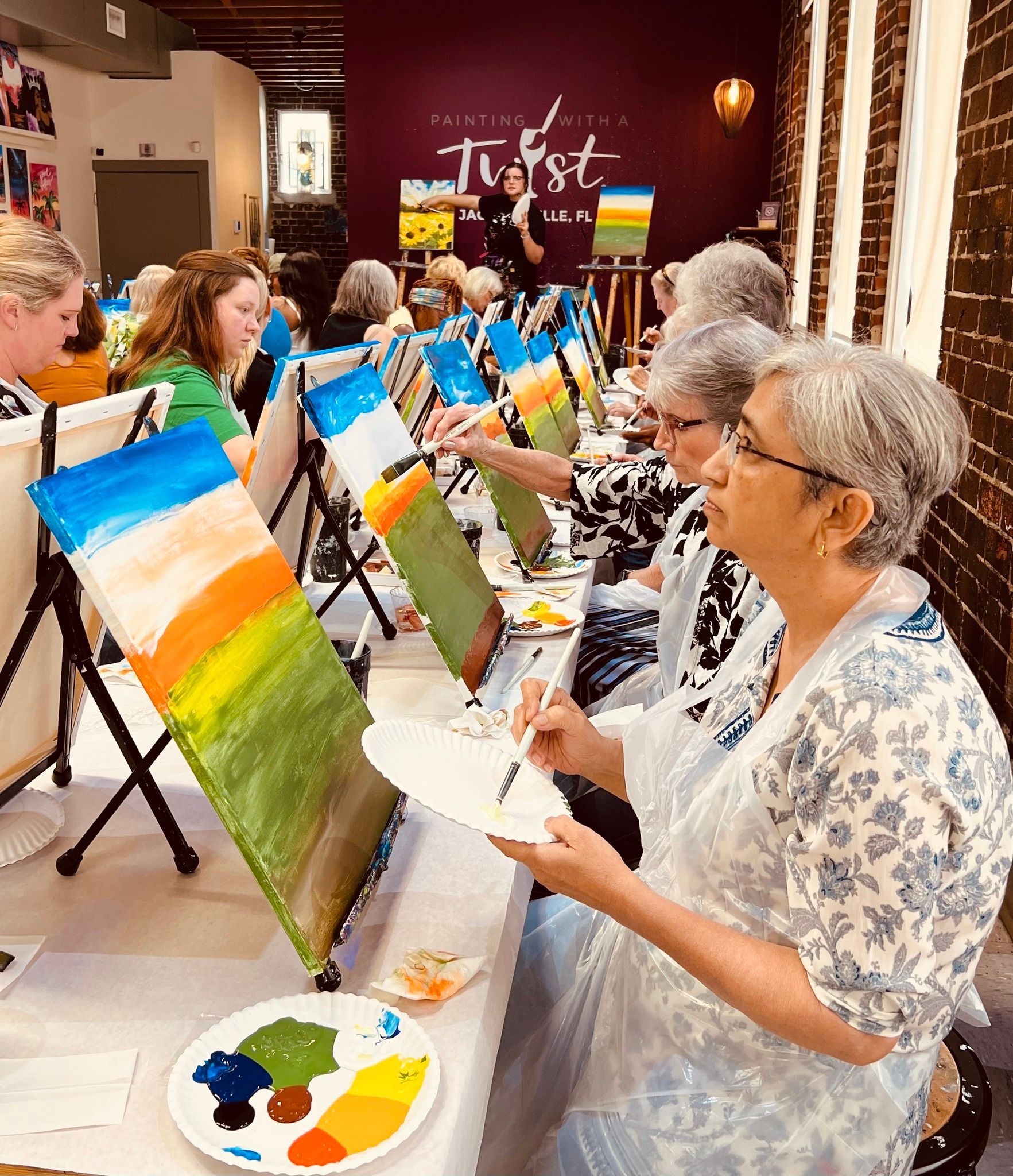 A group of people are sitting at a table painting.
