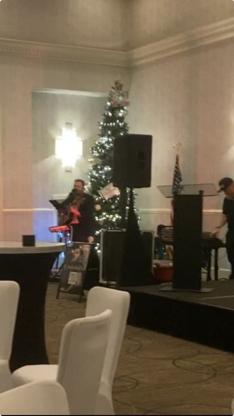A man is playing a guitar in a room with a christmas tree in the background
