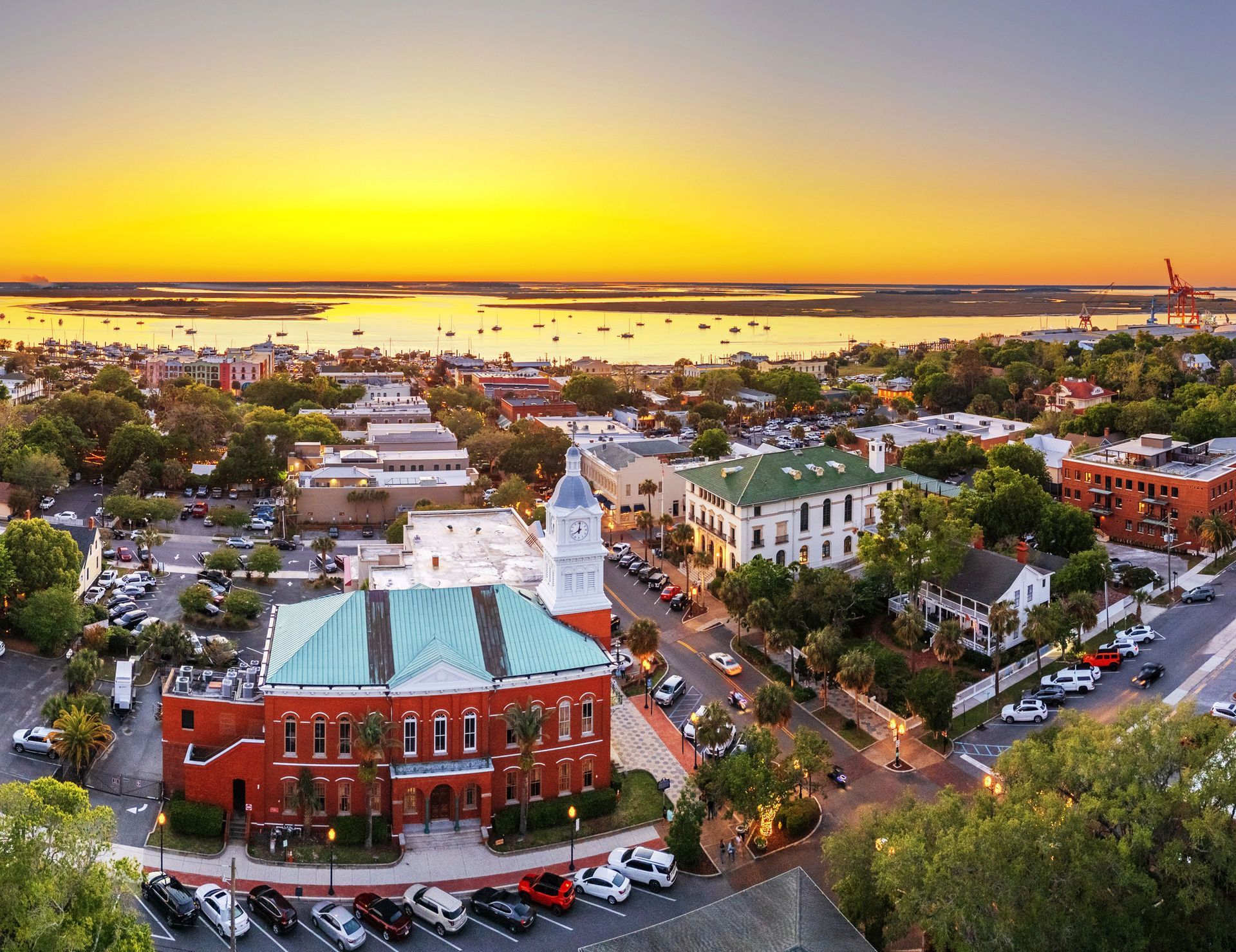 Sunset aerial view of Fernandina Beach, Florida with historic buildings, trees, and streets along the harbor,
