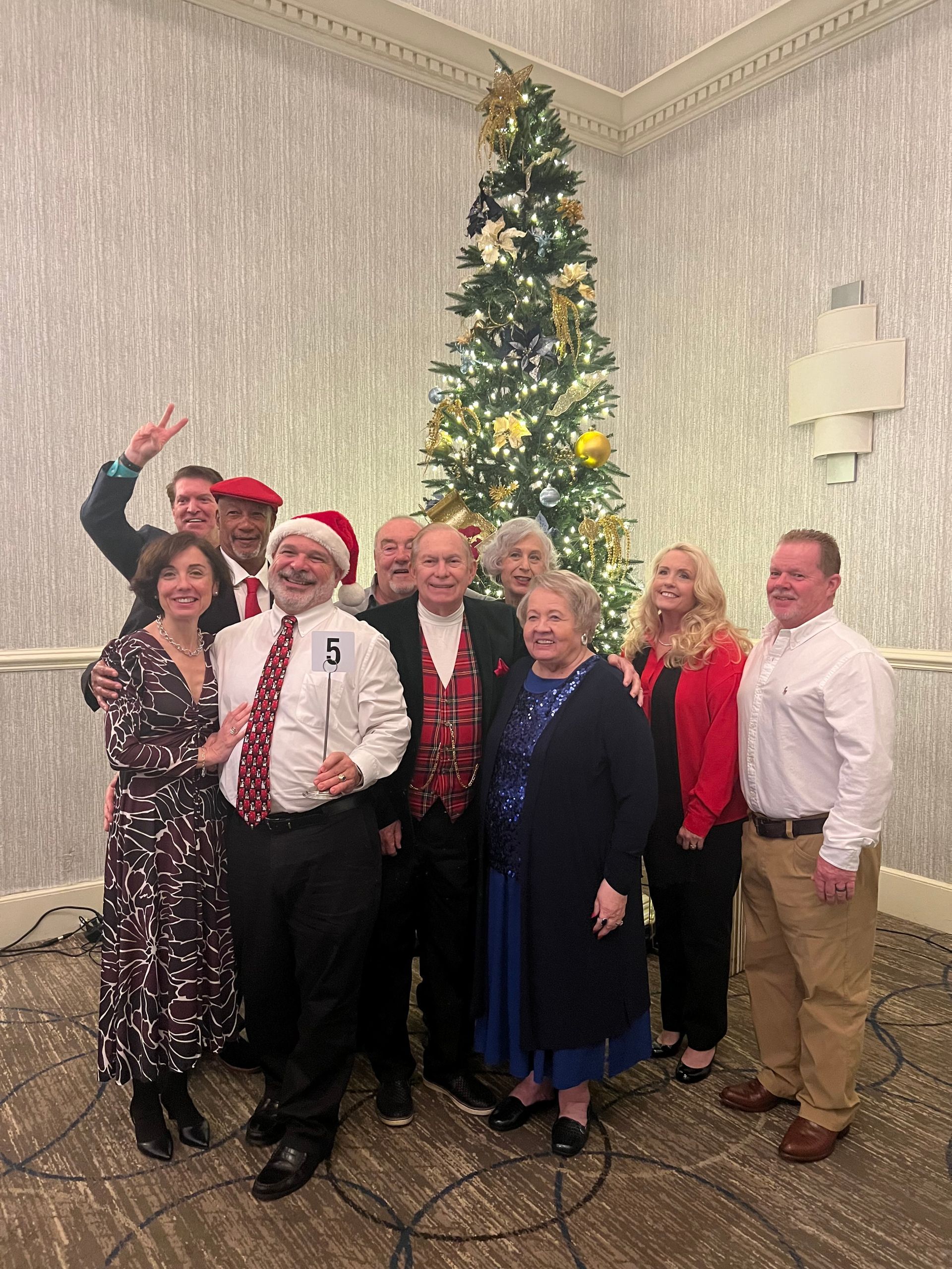 A group of people are posing for a picture in front of a christmas tree.