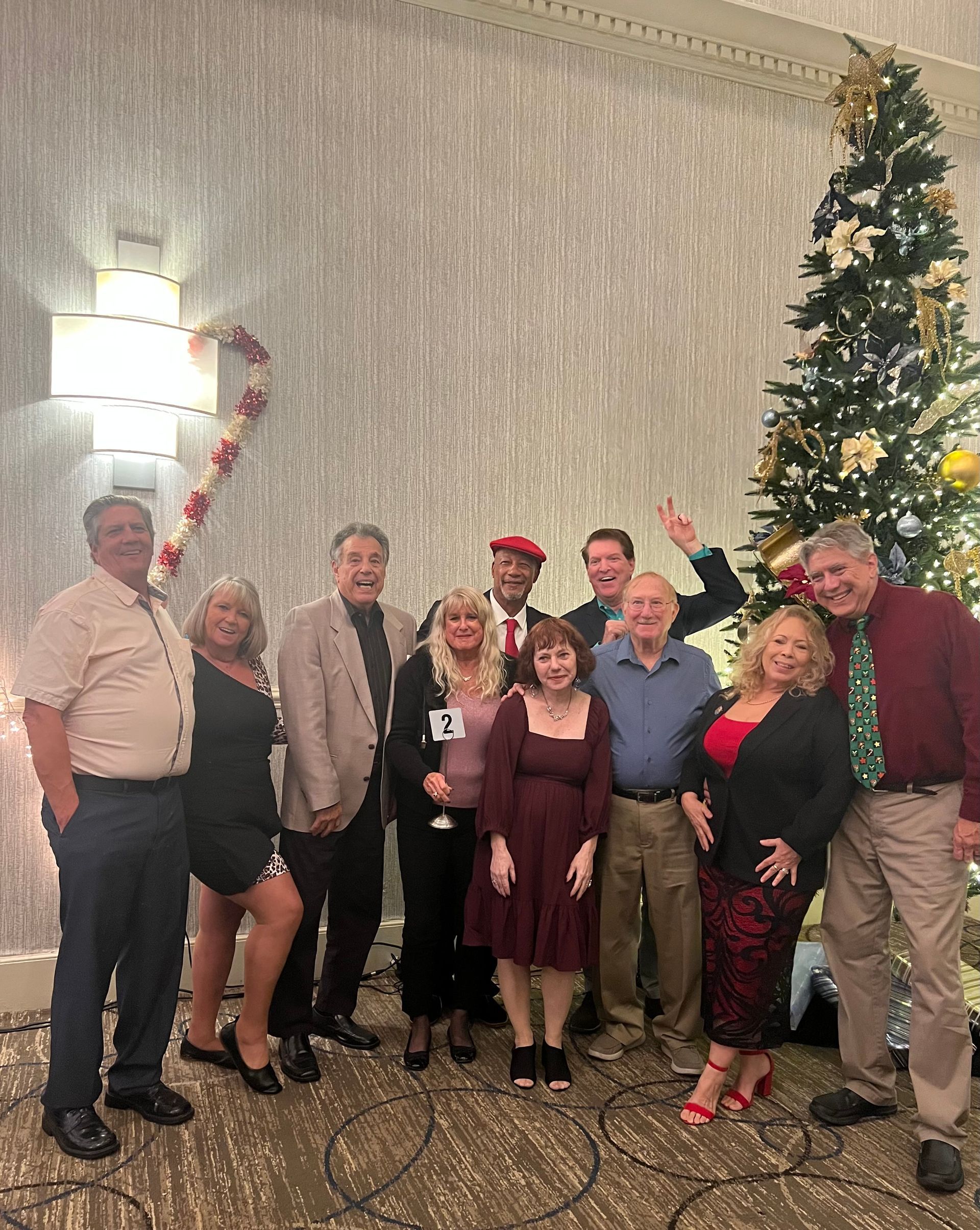 A group of people are posing for a picture in front of a christmas tree.