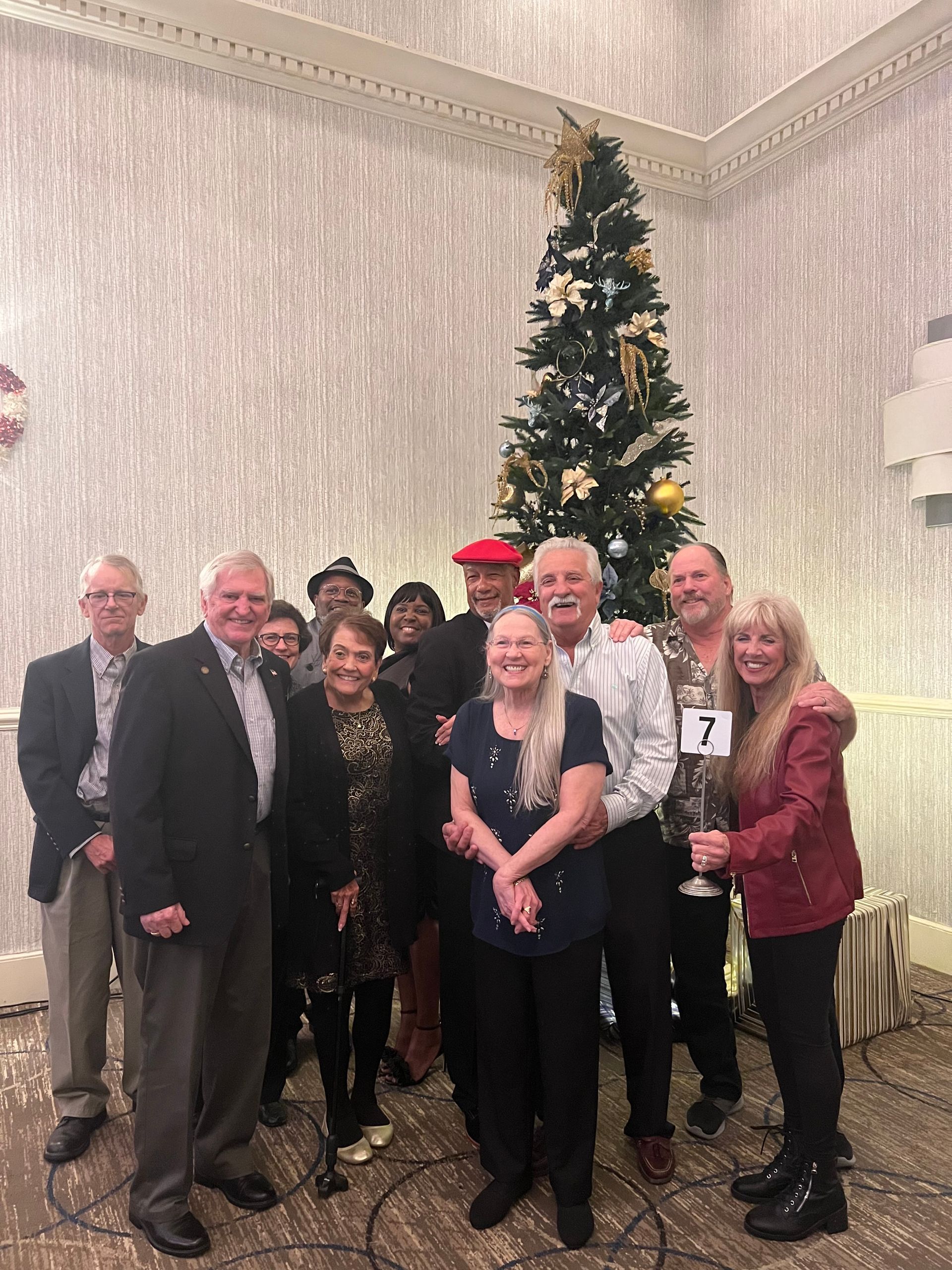 A group of people are posing for a picture in front of a christmas tree.