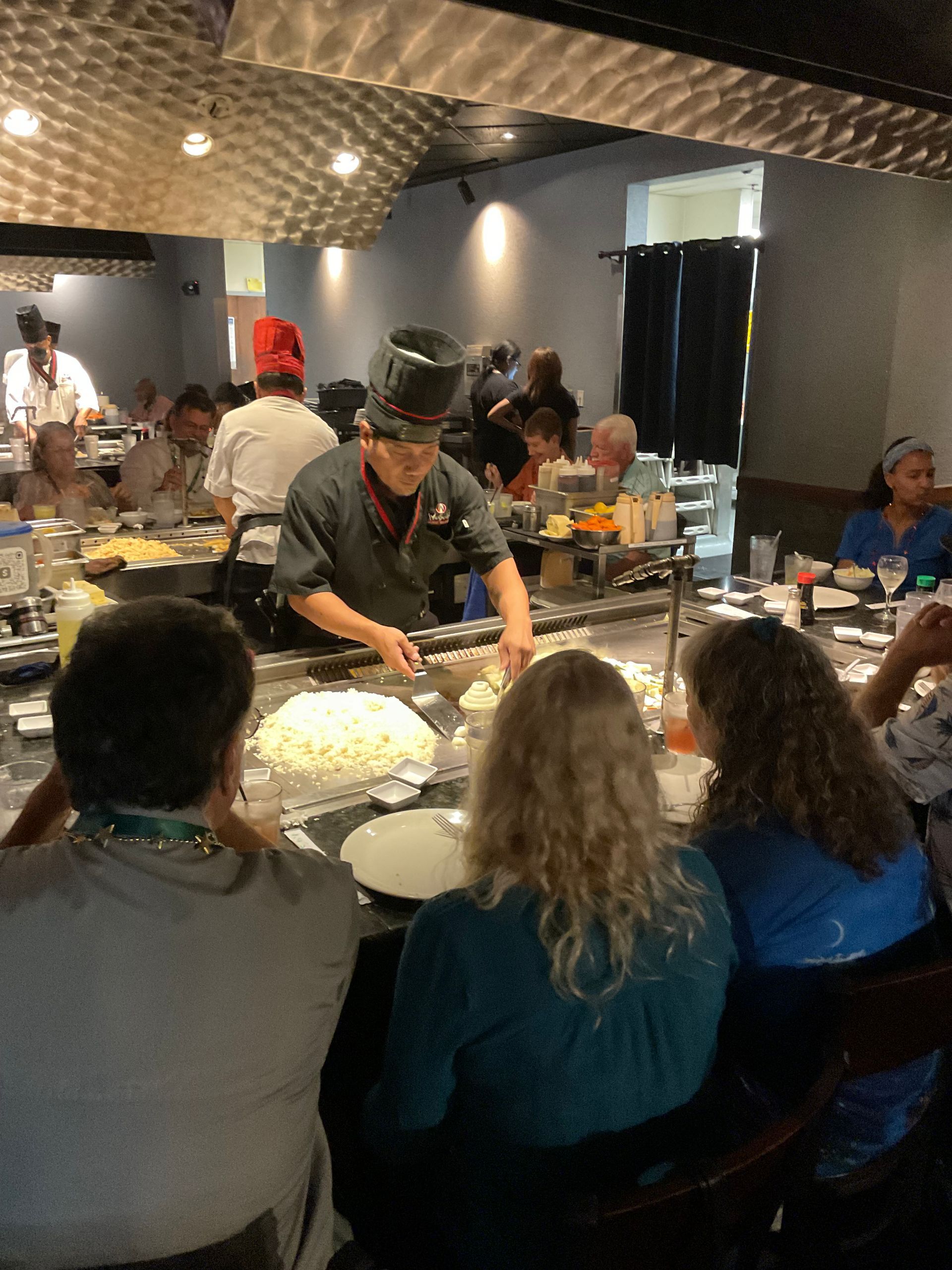 A group of people are watching the chef prepare hibachi food