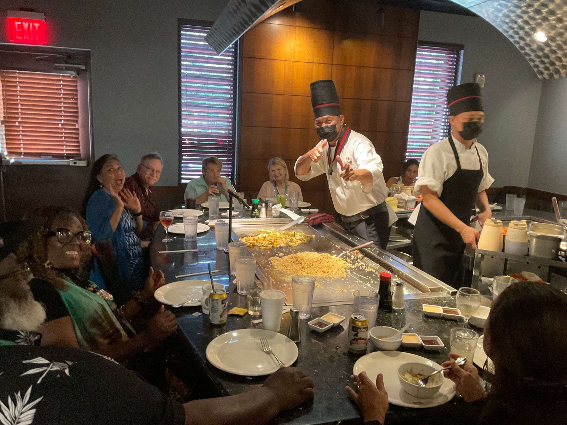 A group of people are sitting at a hibachi table watching the chef cook food
