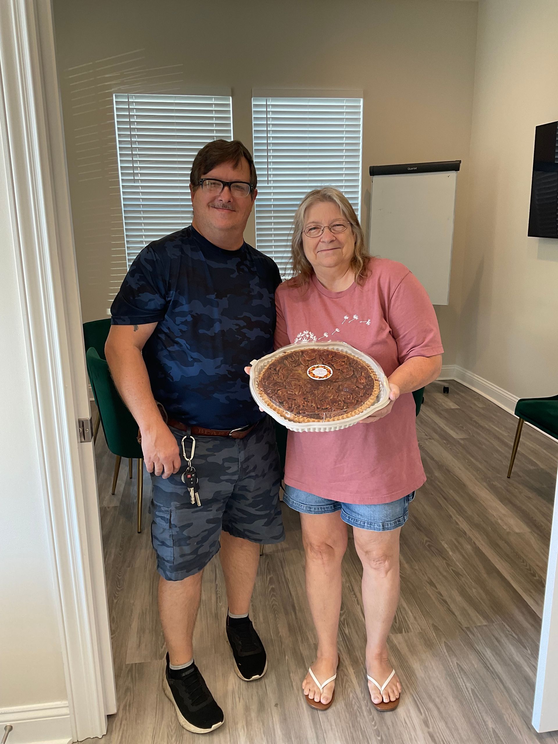 A man and a woman are standing next to each other holding a pie.